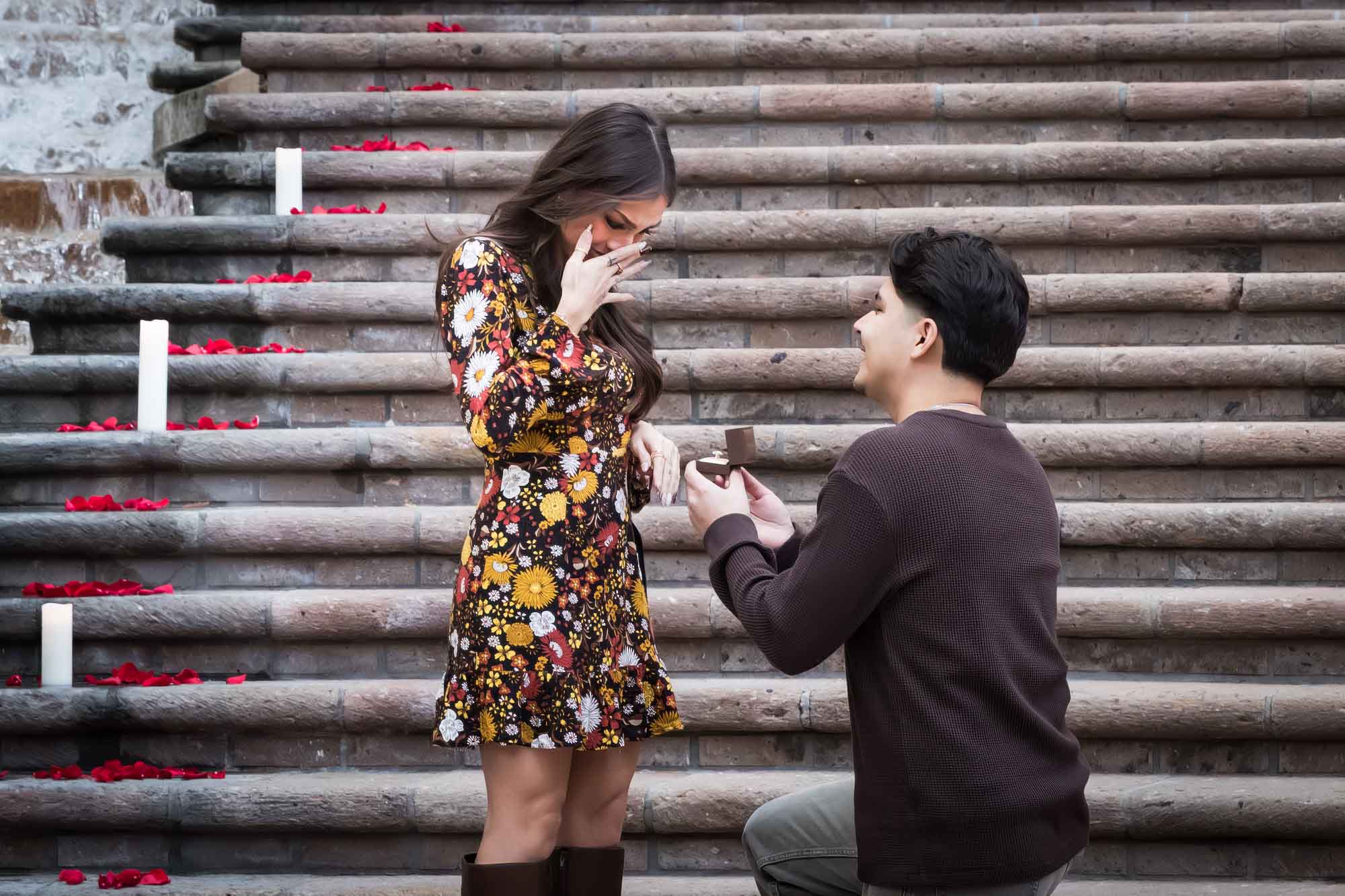 Man proposing to woman at the base of the stairs of the Weston Centre during a downtown San Antonio surprise proposal