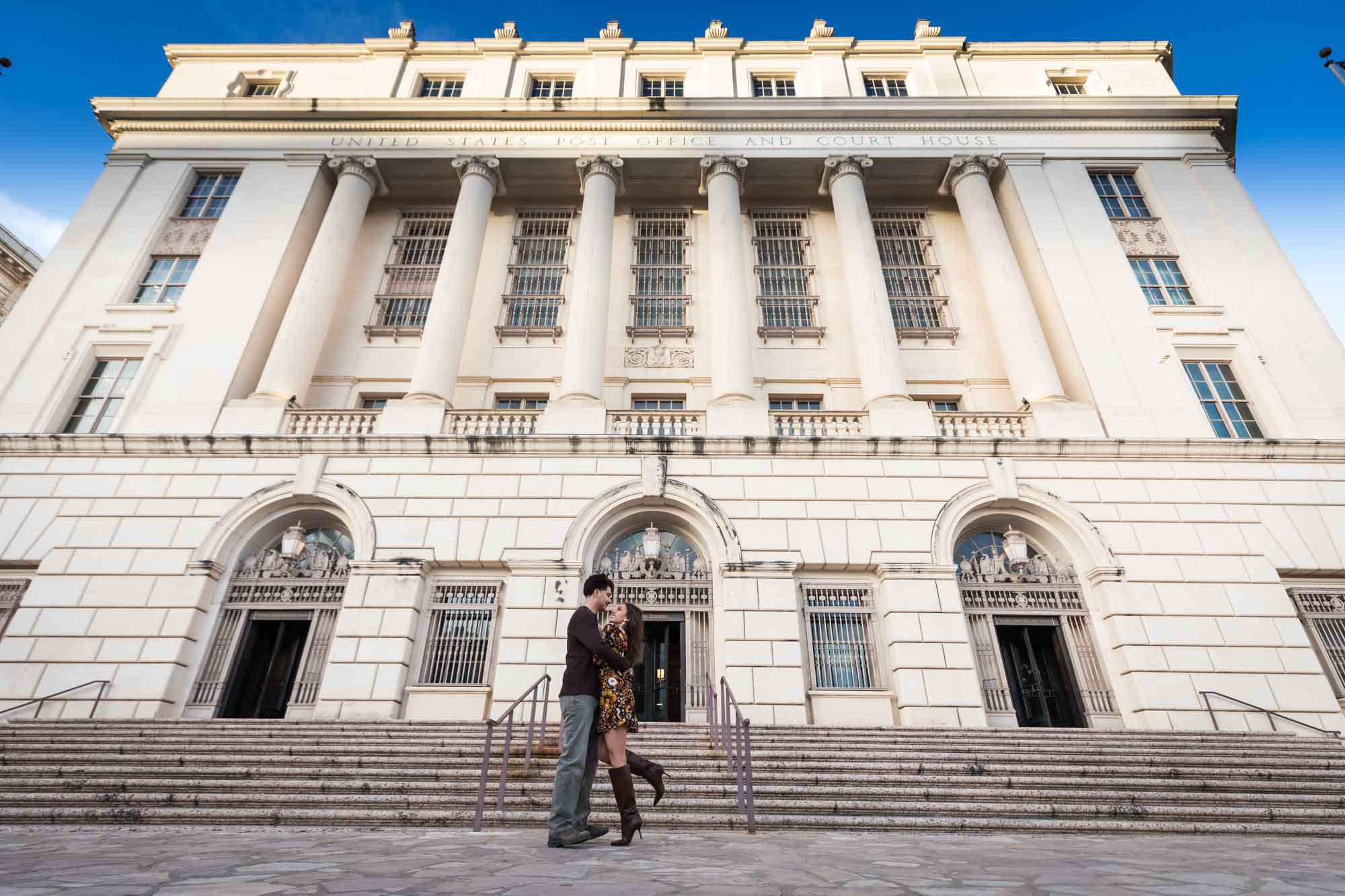 Couple hugging on stairs of Houston Street post office during a downtown San Antonio surprise proposal