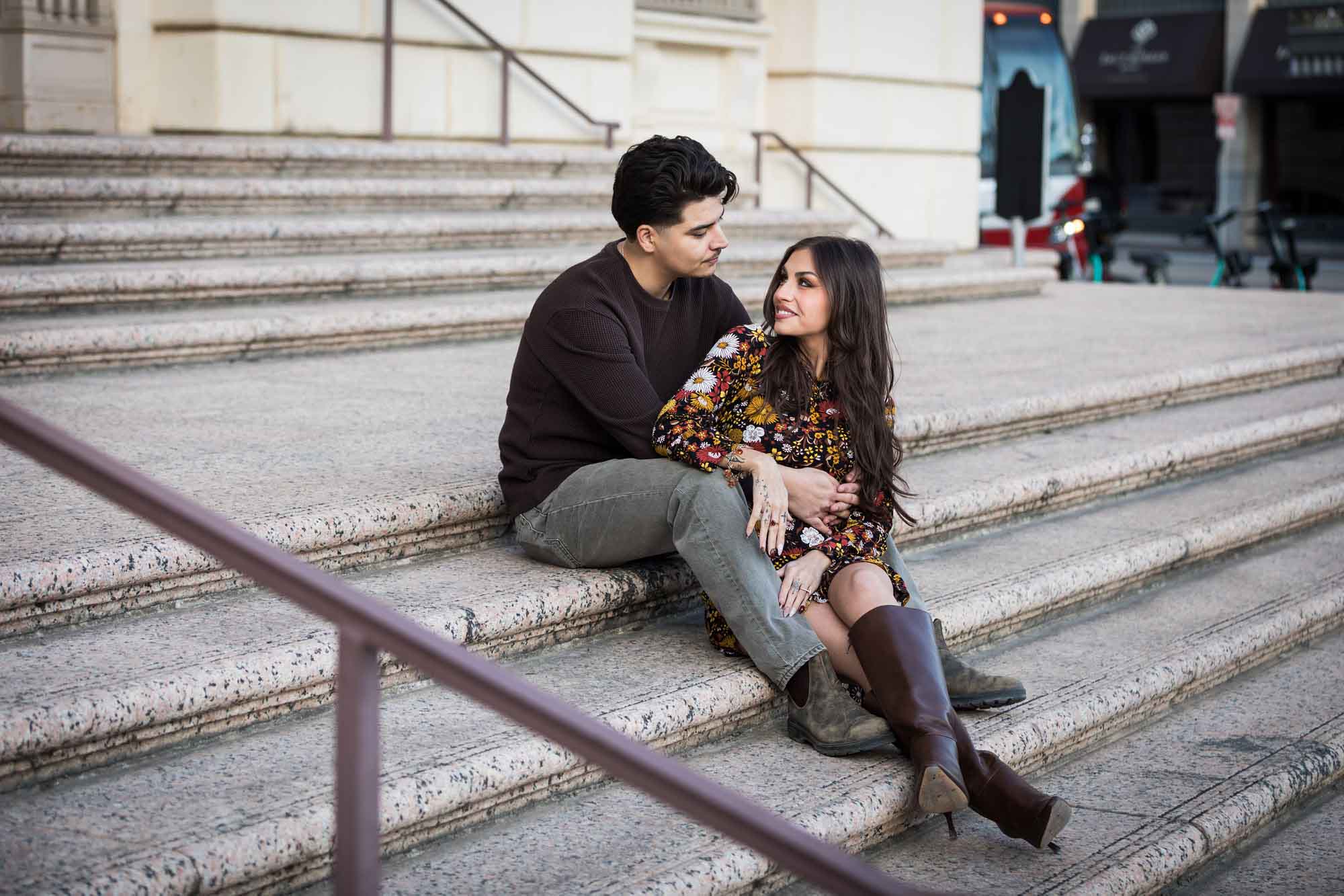 Couple sitting close on stairs of Houston Street post office during a downtown San Antonio surprise proposal