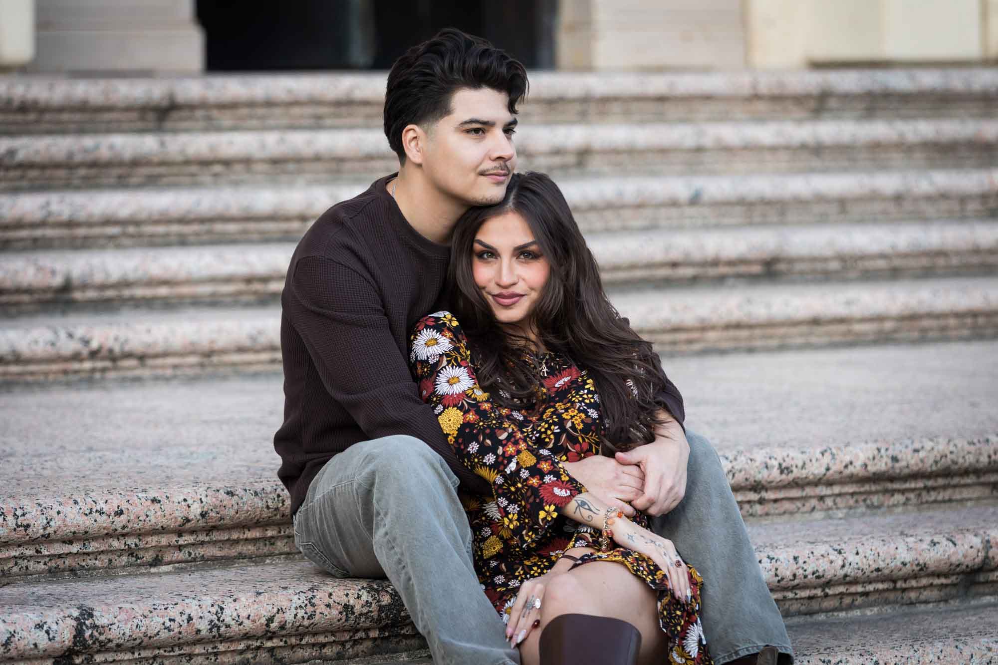 Couple sitting close on stairs of Houston Street post office during a downtown San Antonio surprise proposal