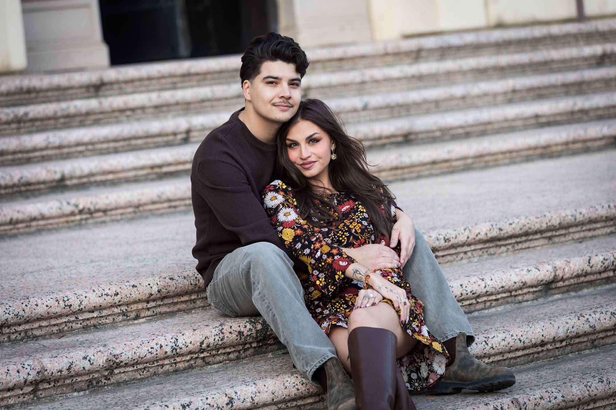 Couple sitting close on stairs of Houston Street post office during a downtown San Antonio surprise proposal