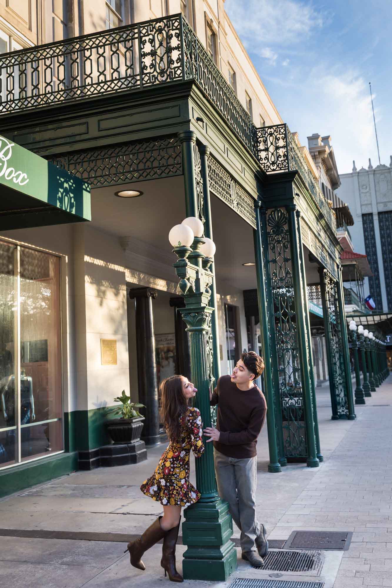 Couple posing in front of green column of Menger Hotel during a downtown San Antonio surprise proposal