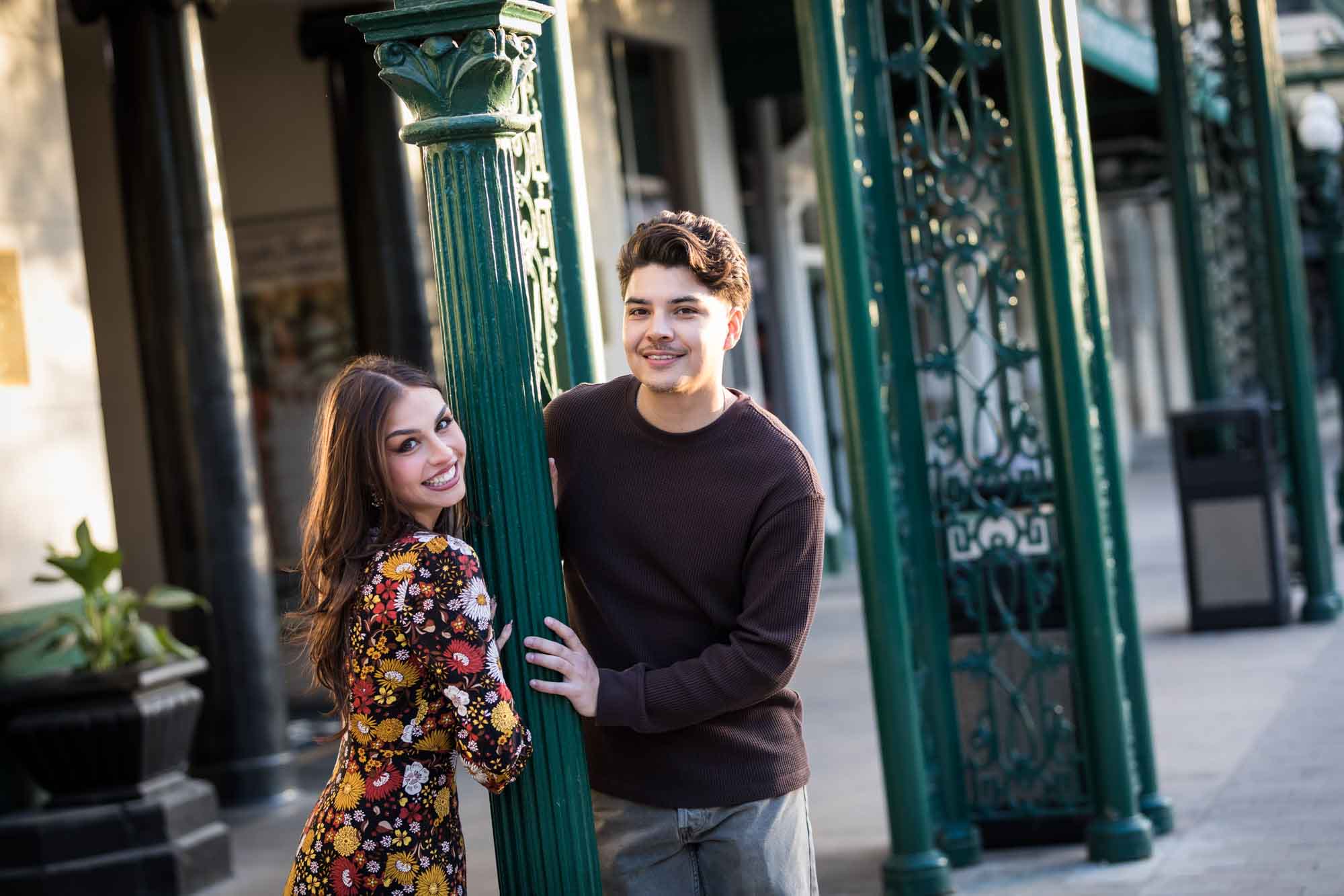 Couple posing in front of green column of Menger Hotel during a downtown San Antonio surprise proposal