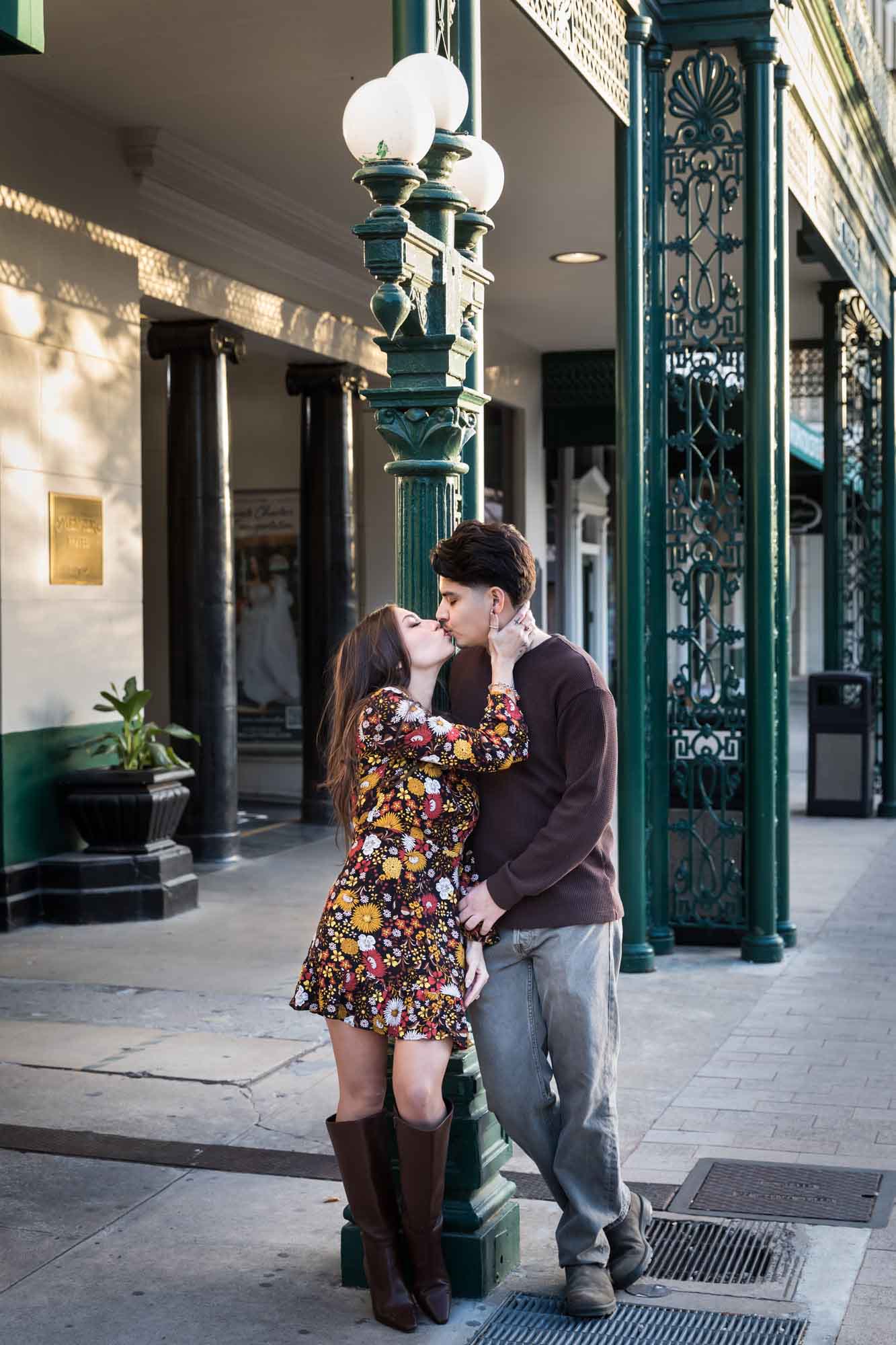 Couple kissing in front of green columns of Menger Hotel during a downtown San Antonio surprise proposal