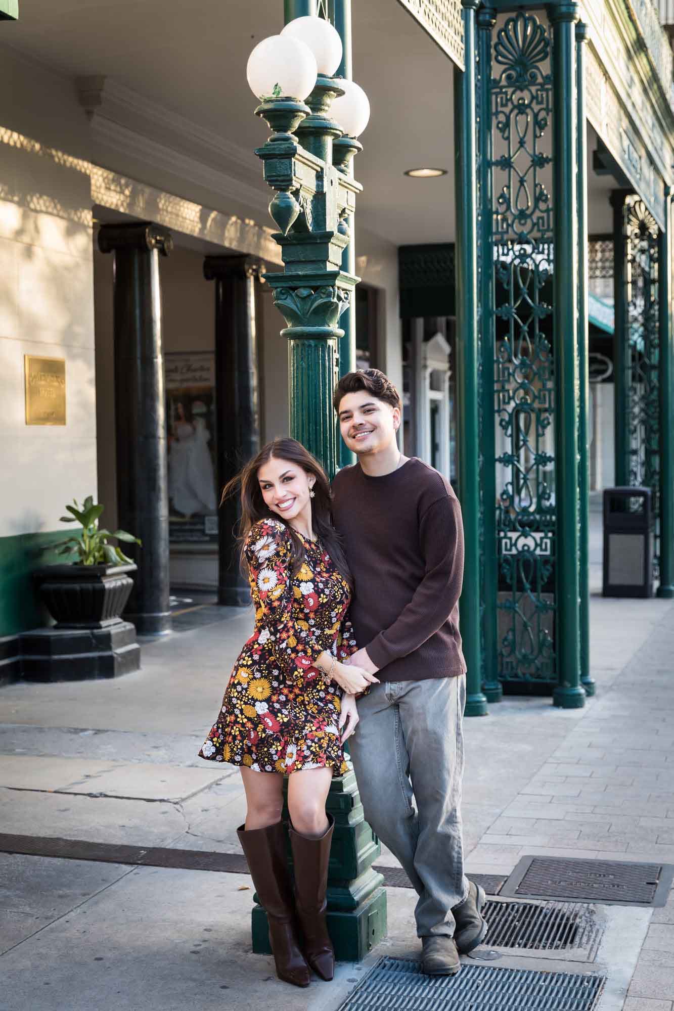 Couple posing in front of green column of Menger Hotel during a downtown San Antonio surprise proposal