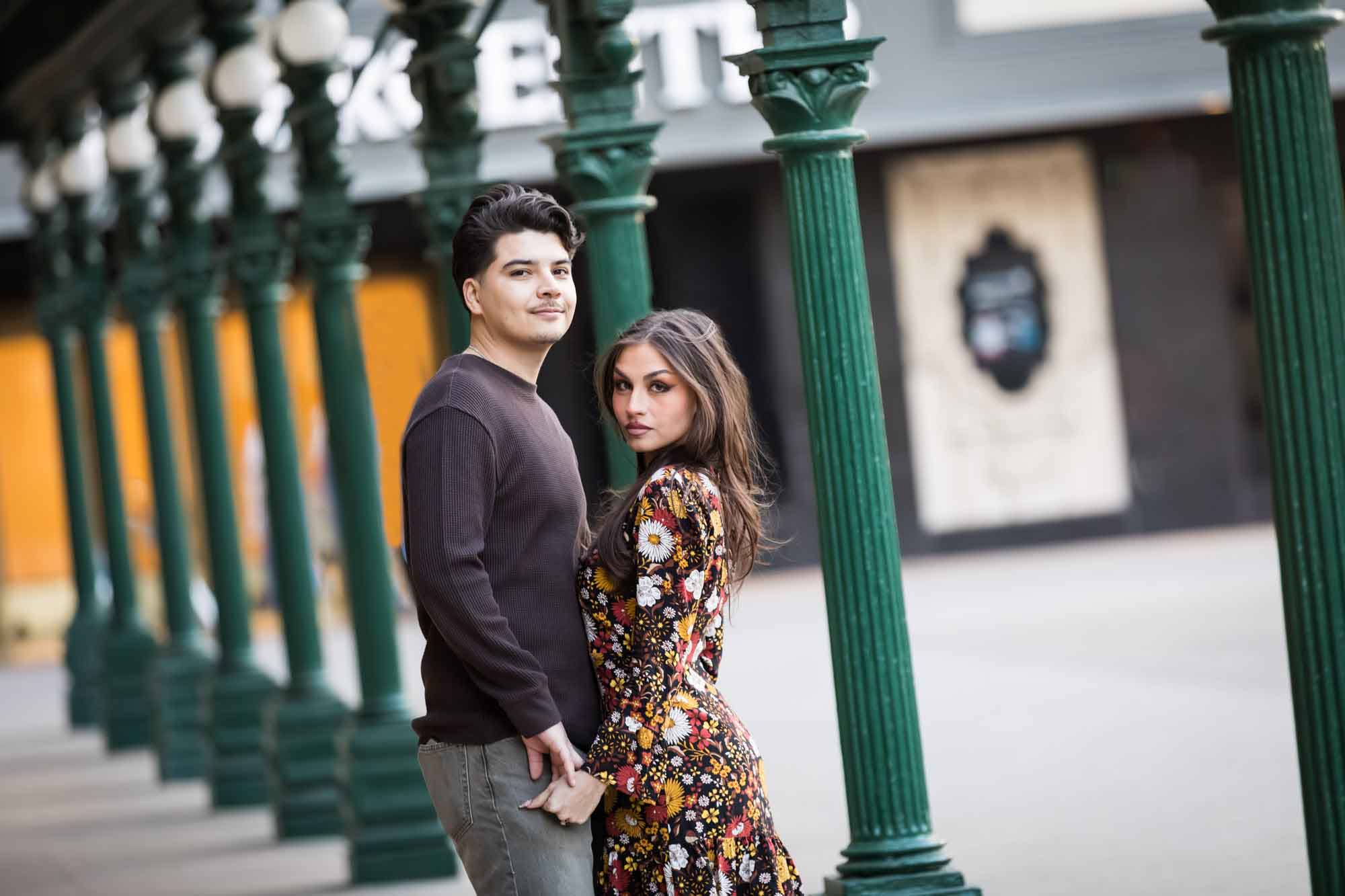 Couple hugging in front of green columns in front of Menger Hotel during a downtown San Antonio surprise proposal