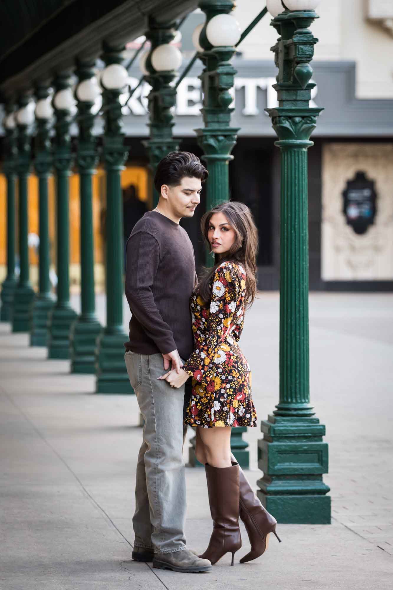 Couple hugging in front of green columns in front of Menger Hotel during a downtown San Antonio surprise proposal
