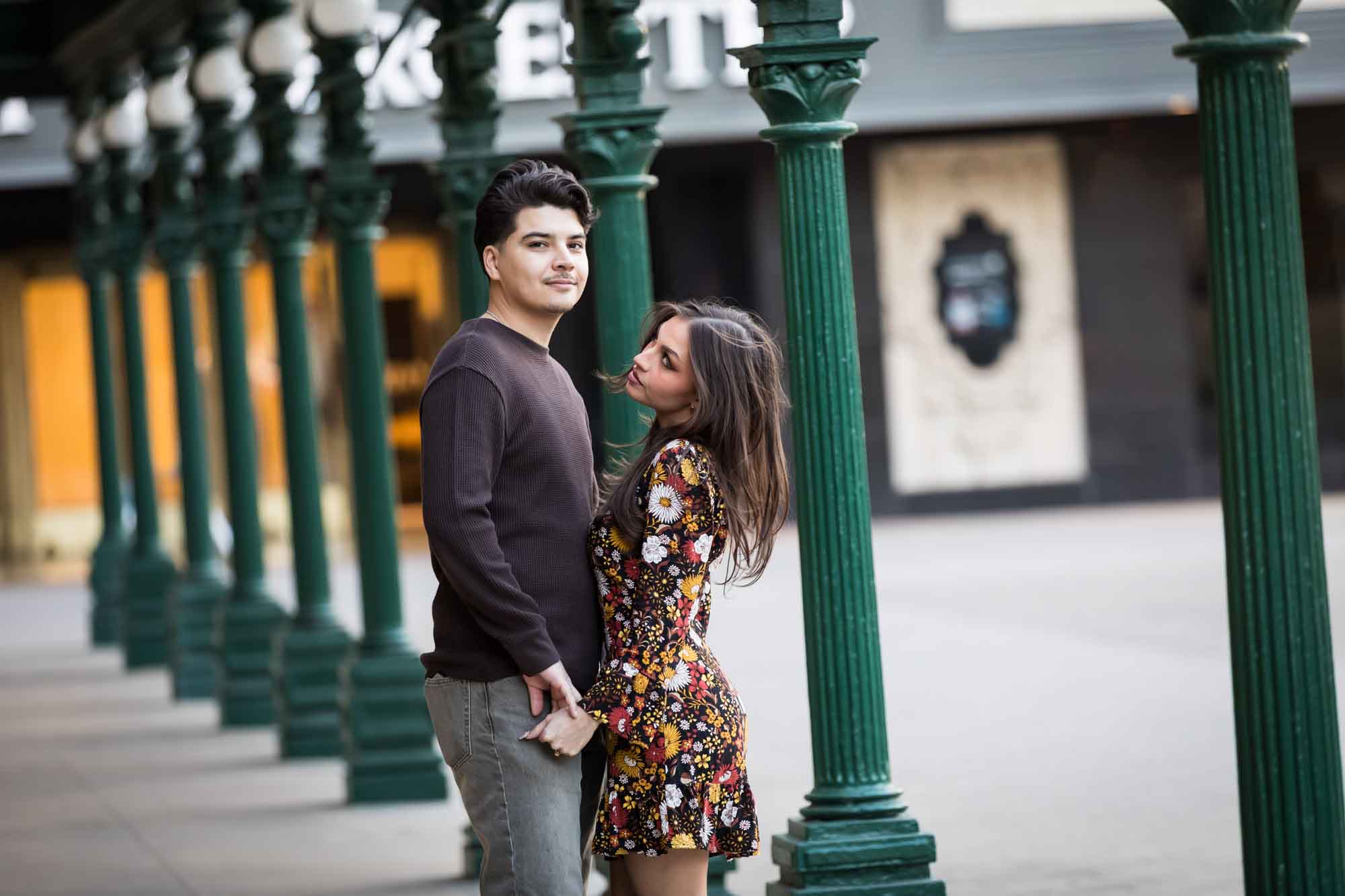 Couple hugging in front of green columns in front of Menger Hotel during a downtown San Antonio surprise proposal