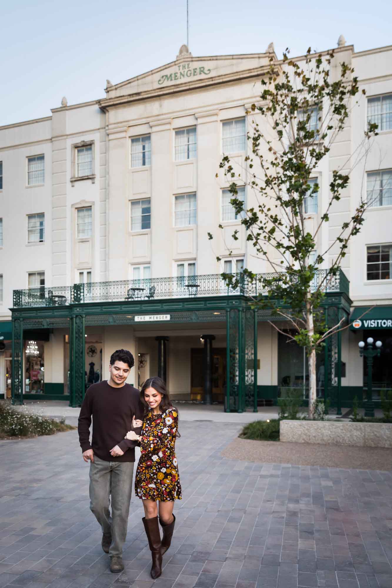 Man and woman walking arm-in-arm in front of Menger Hotel during a downtown San Antonio surprise proposal