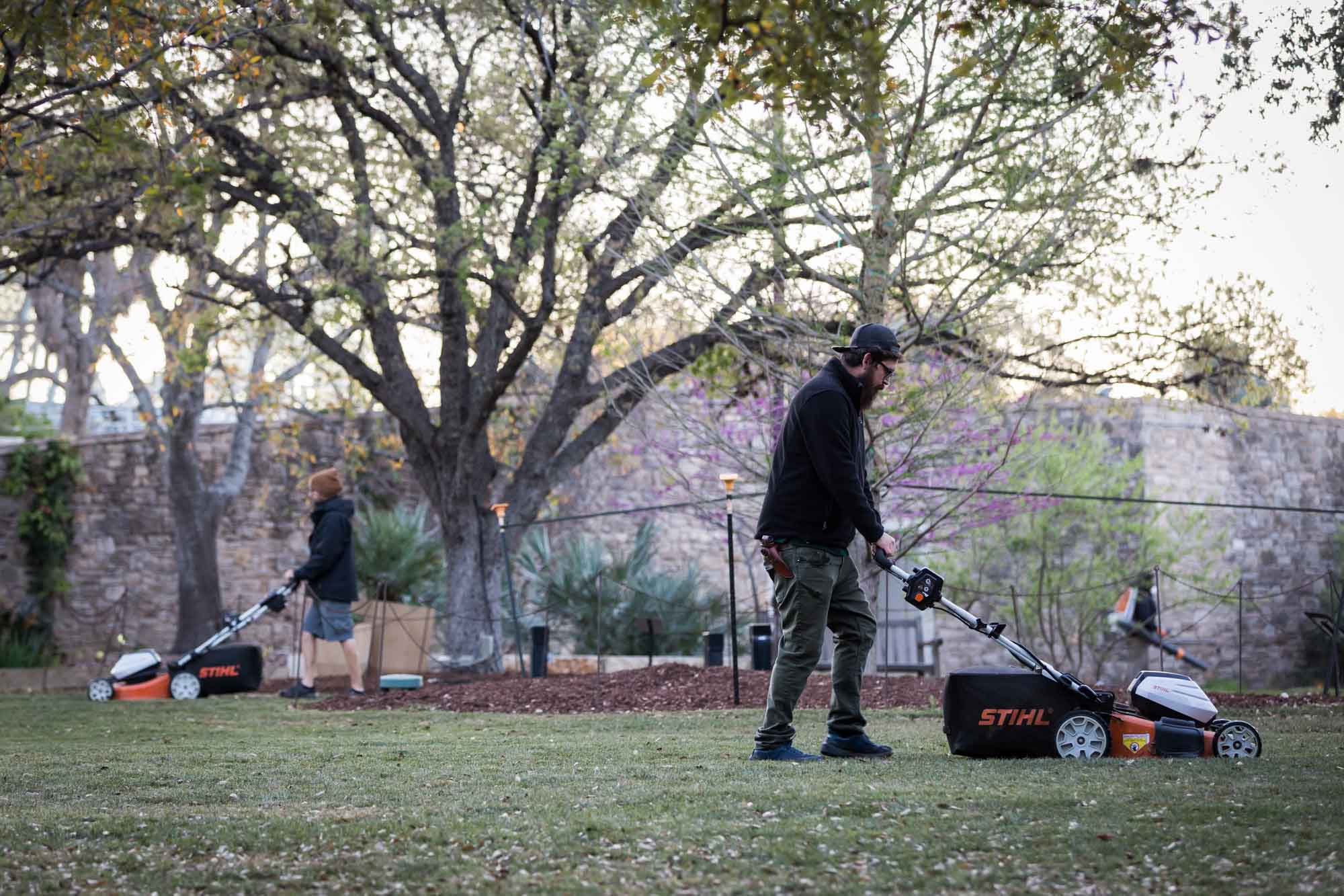 Workers collecting leaves with lawnmowers on the lawn before a San Antonio Botanical Garden wedding ceremony