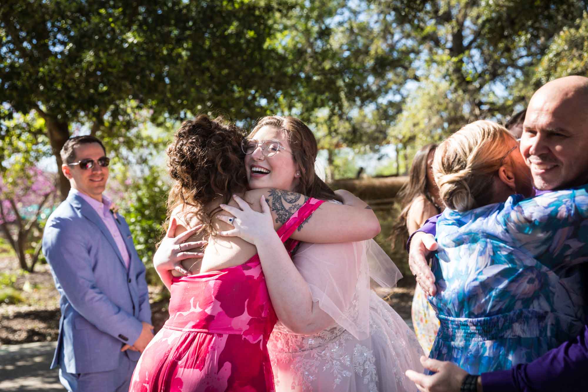 Bride and guests laughing and hugging after a San Antonio Botanical Garden wedding ceremony