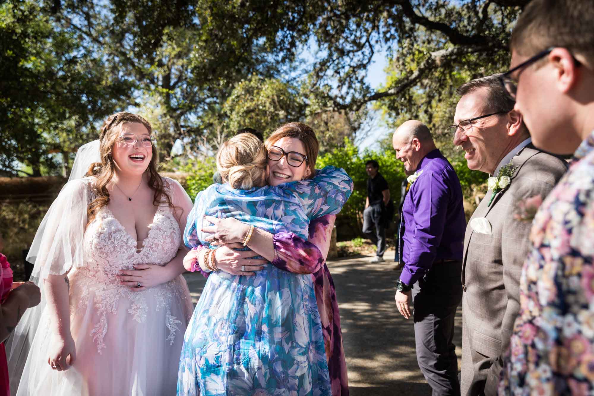 Bride and guests hugging and laughing after a San Antonio Botanical Garden wedding ceremony
