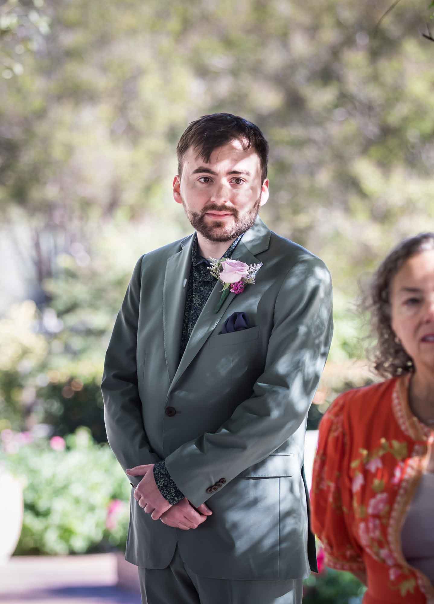Groom watching behind guests during a San Antonio Botanical Garden wedding ceremony