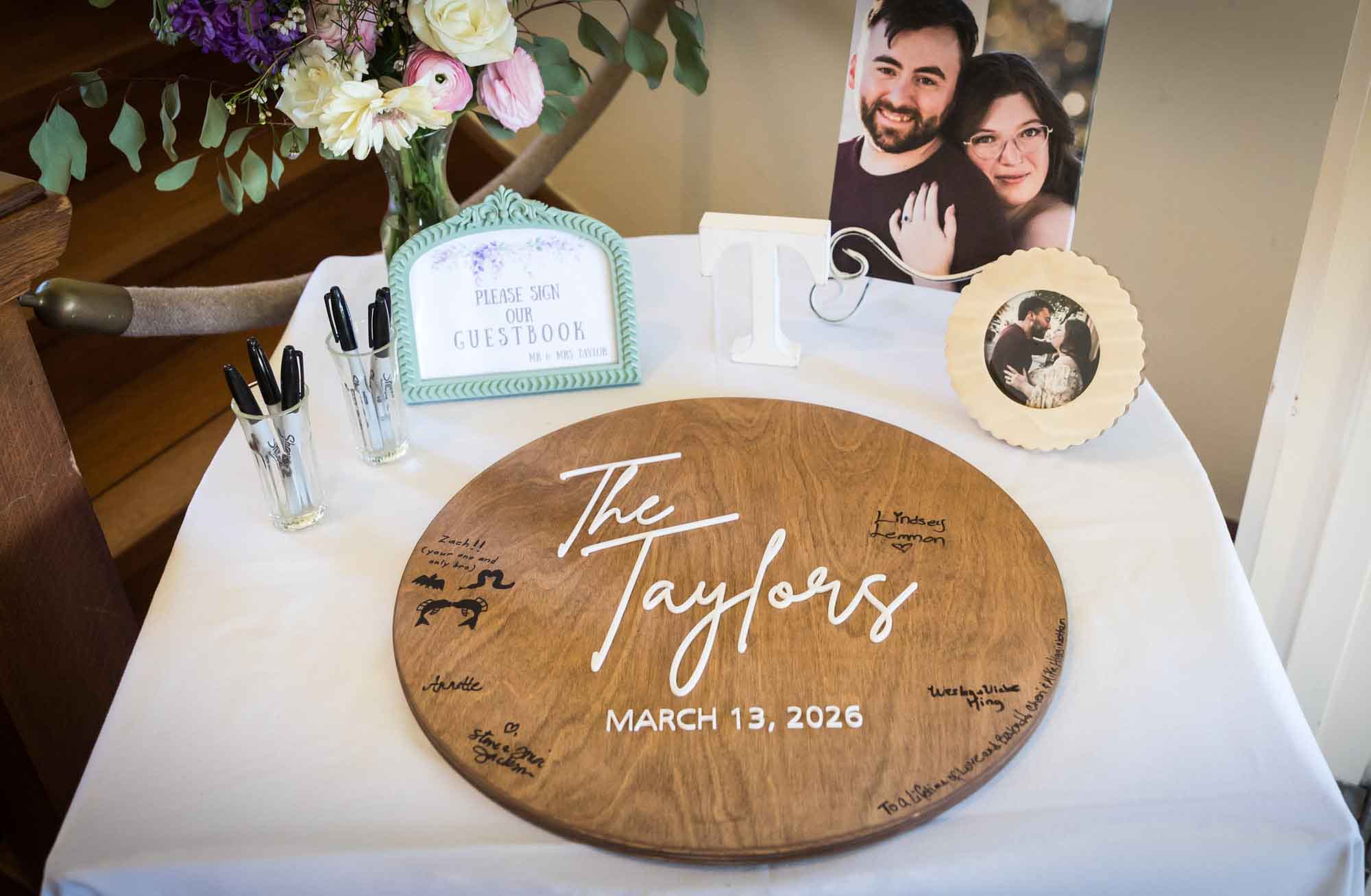Table holding round wooden plaque for guest book during a Guenther House wedding reception