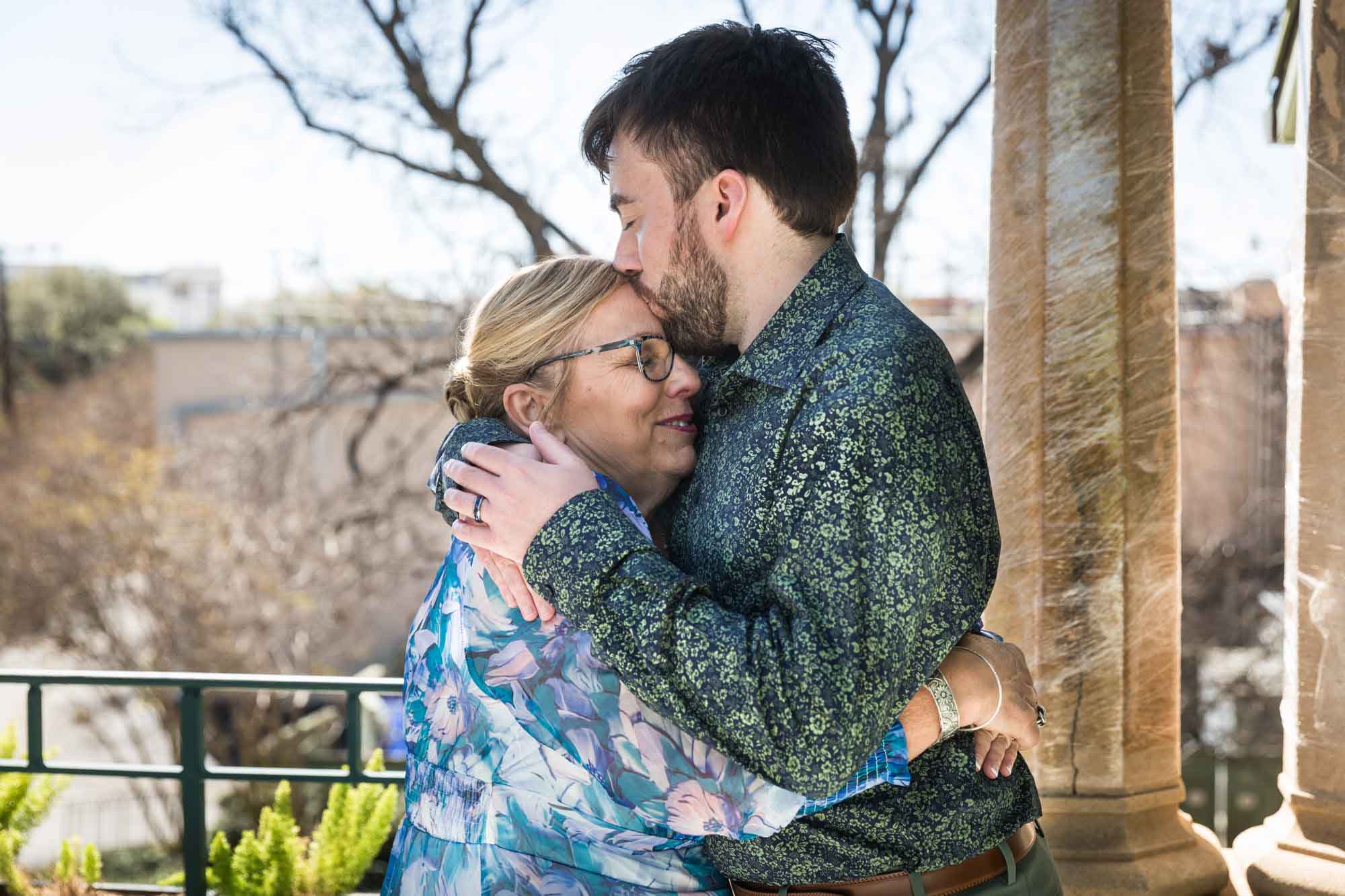 Man kissing woman wearing blue floral dress on the forehead during a Guenther House wedding reception