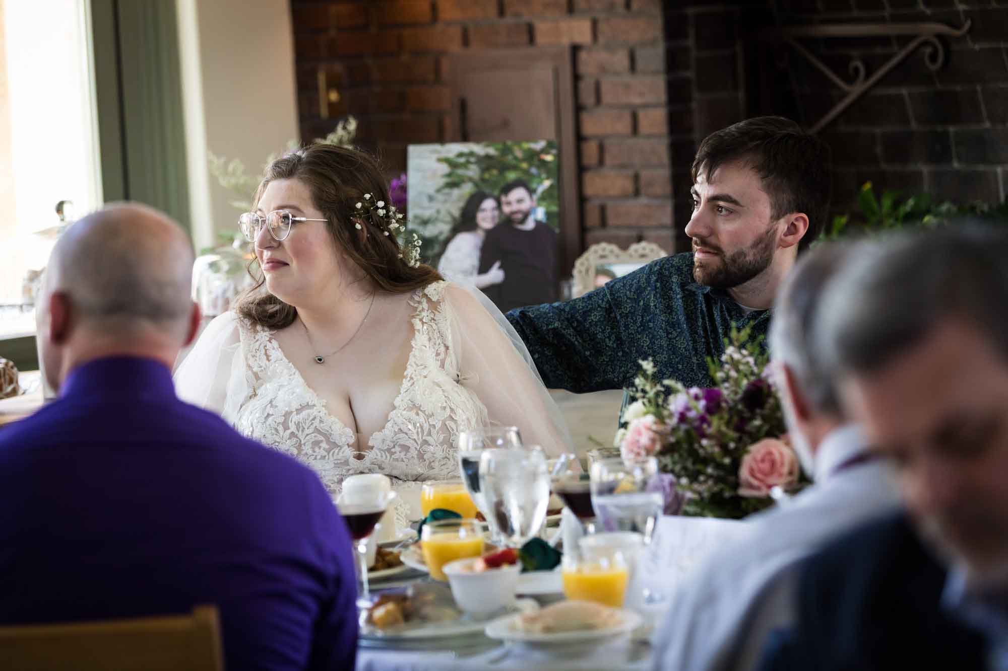Bride and groom seated in front of guests listening to speeches during a Guenther House wedding reception