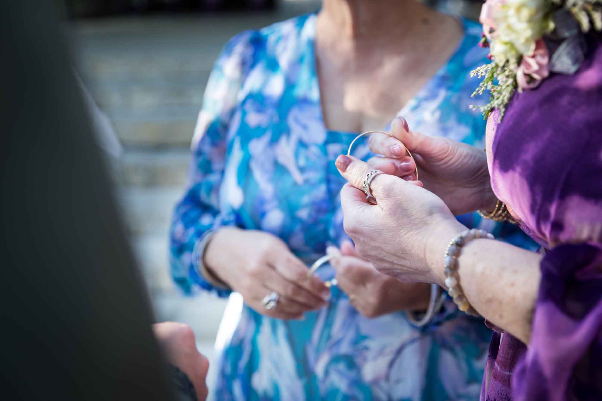 Close up of woman's hands inspecting gold bracelets before a San Antonio Botanical Garden wedding ceremony
