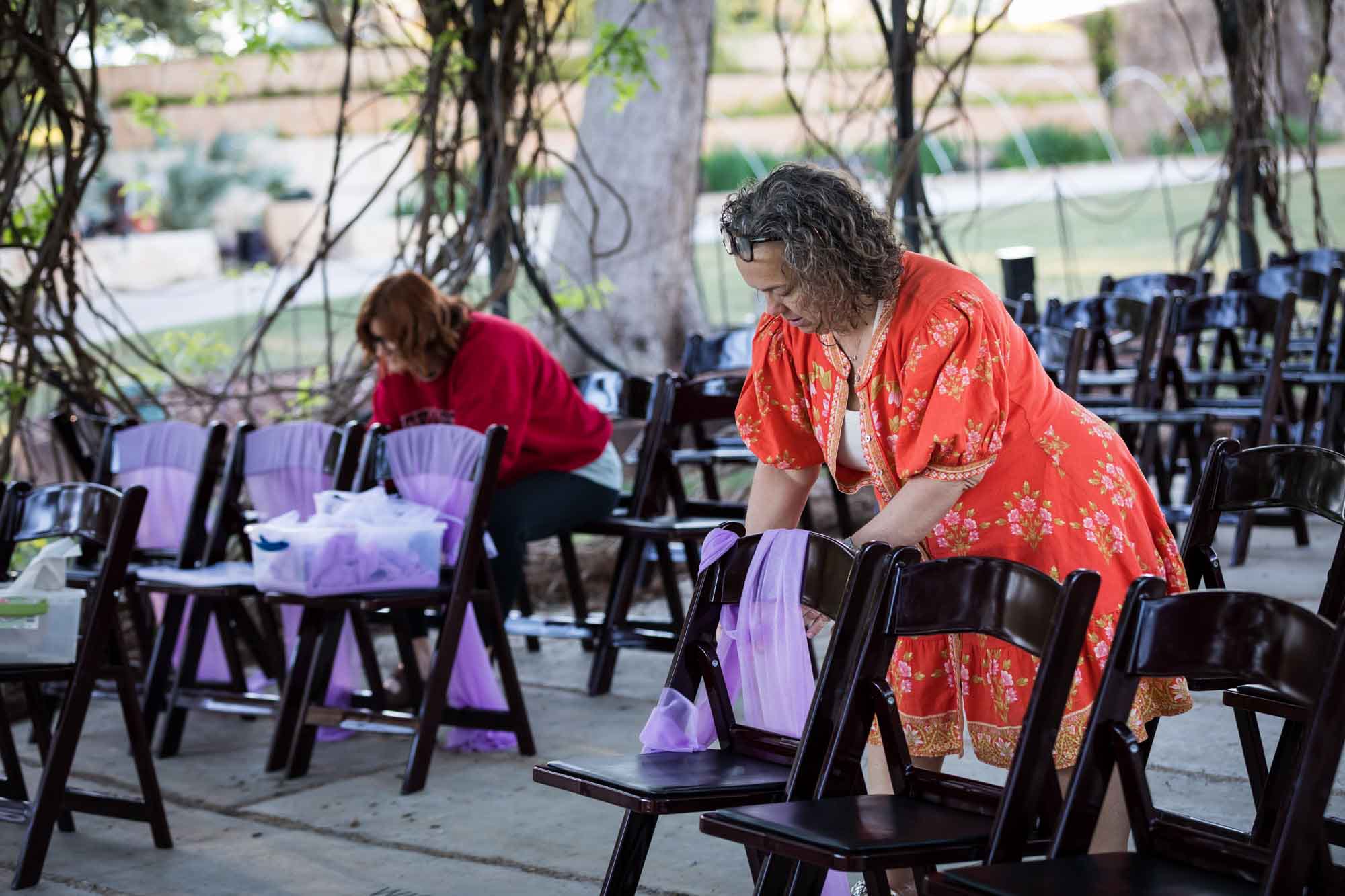 Two women wrapping chairs with purple fabric before a San Antonio Botanical Garden wedding ceremony