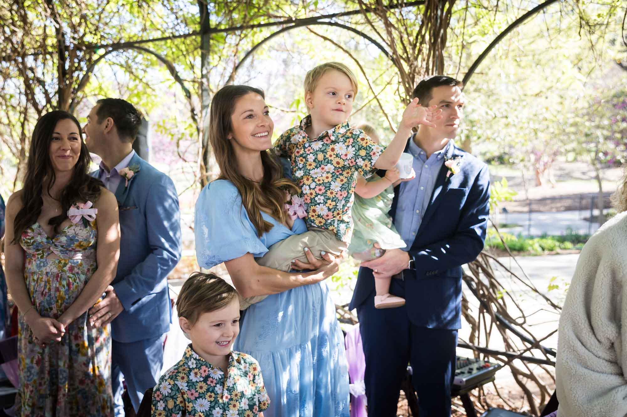 Family holding children in front of other guests during a San Antonio Botanical Garden wedding ceremony