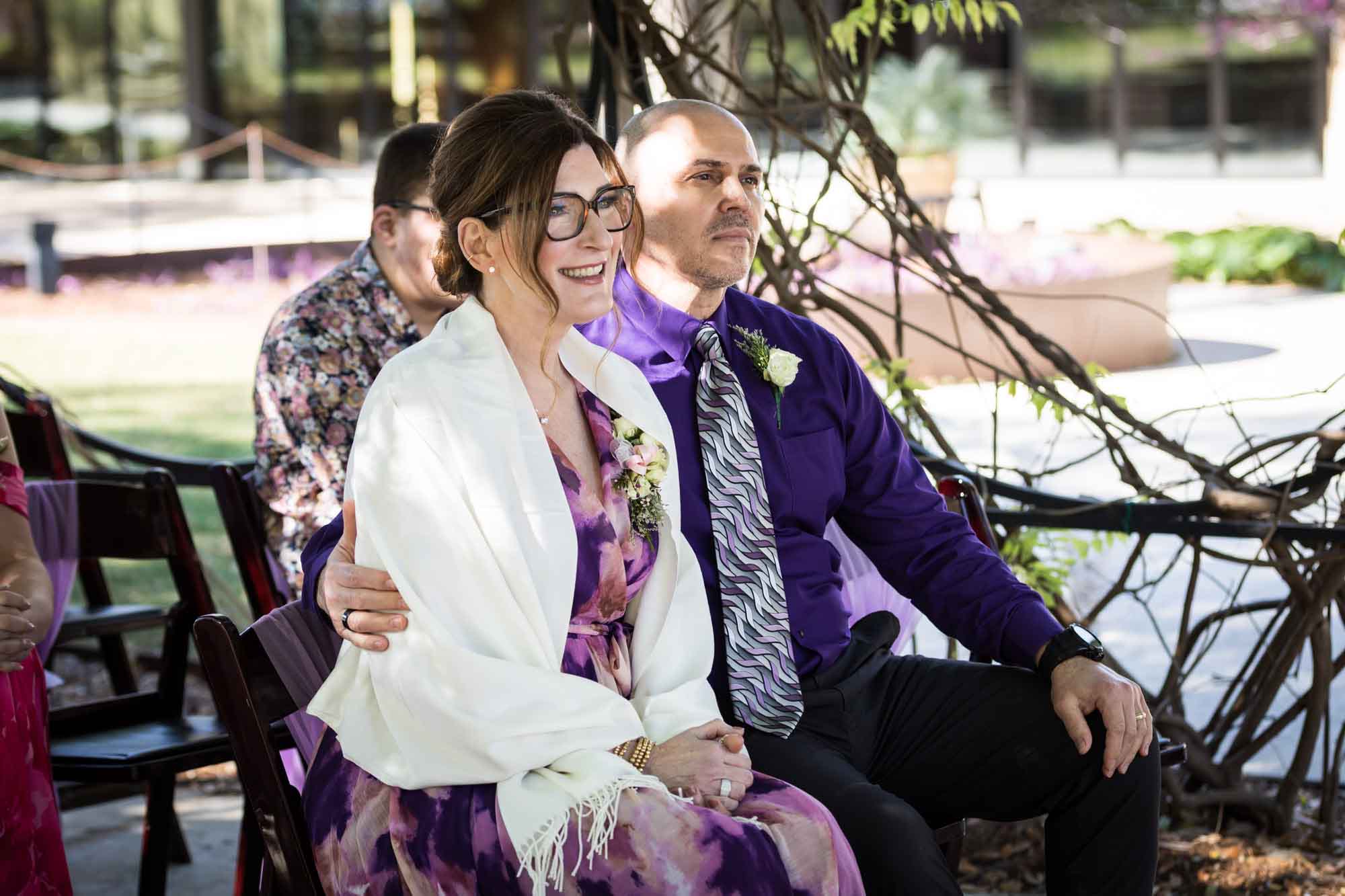 Mother and father sitting under Wisteria Arbor during a San Antonio Botanical Garden wedding ceremony