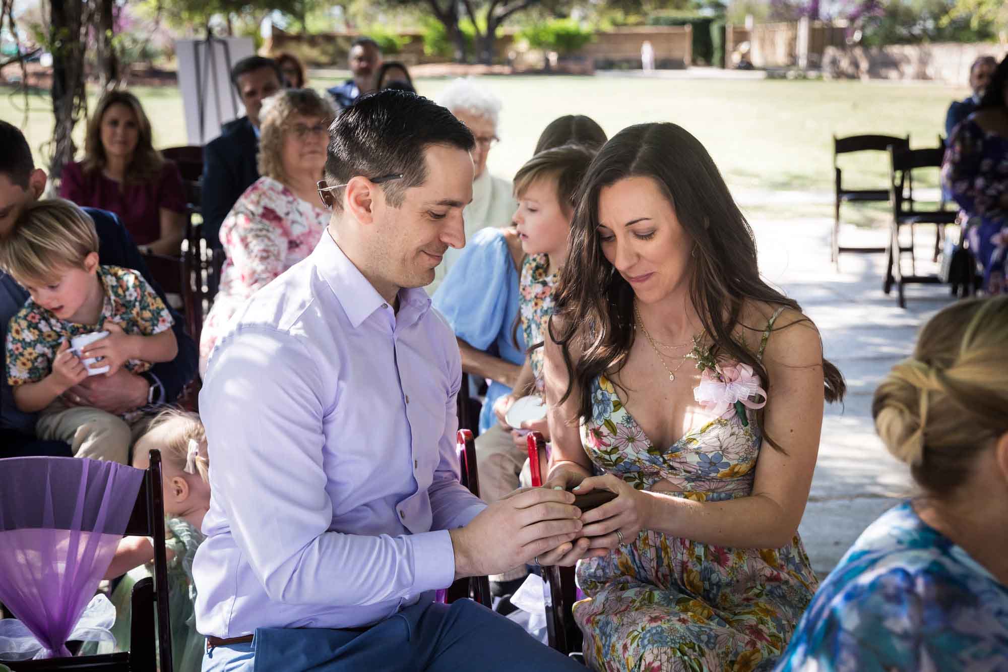 Couple holding wooden box during ring-warming ceremony in front of seated guests during a San Antonio Botanical Garden wedding ceremony
