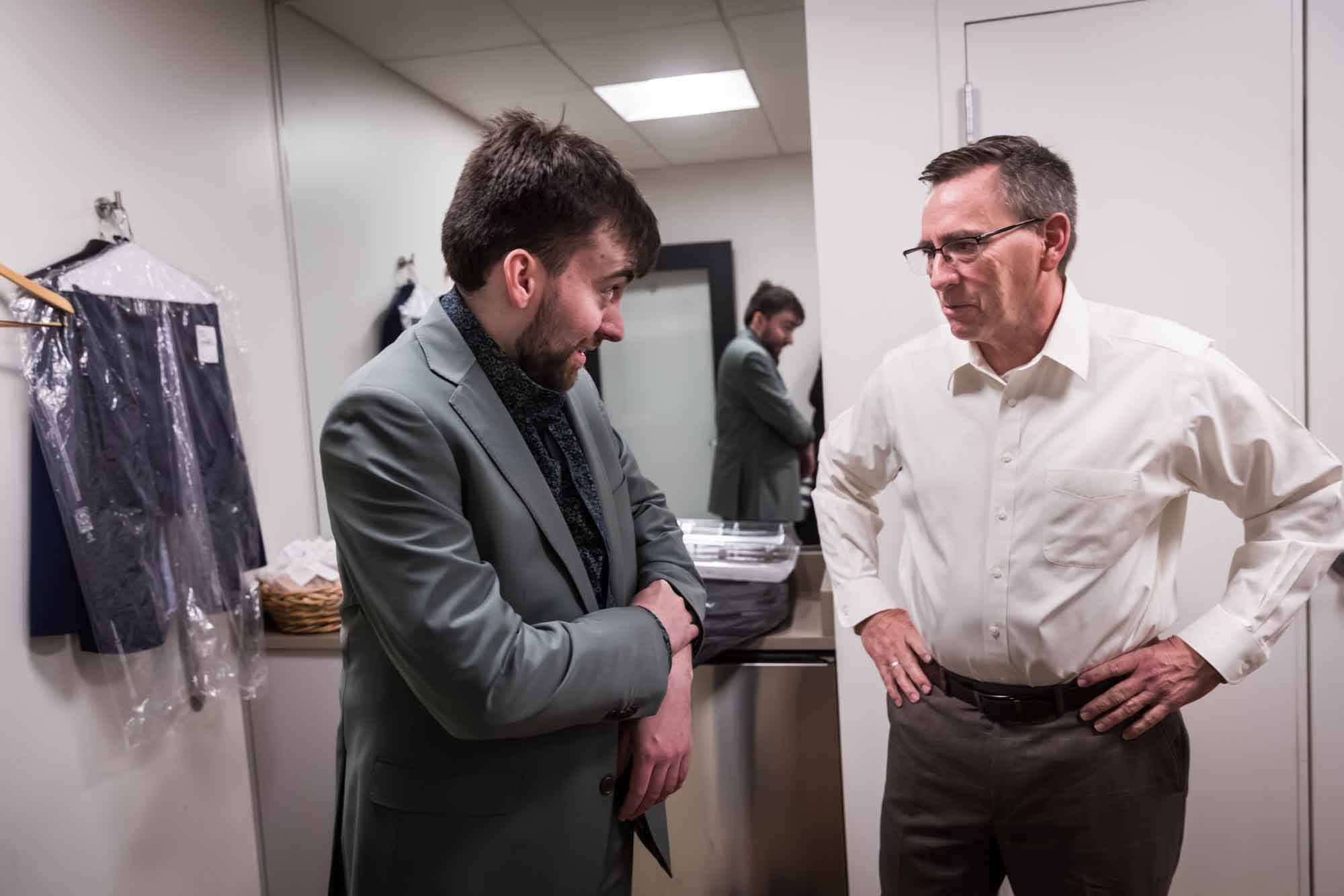 Groom pulling down his sleeve looking to his father in a room before a San Antonio Botanical Garden wedding ceremony