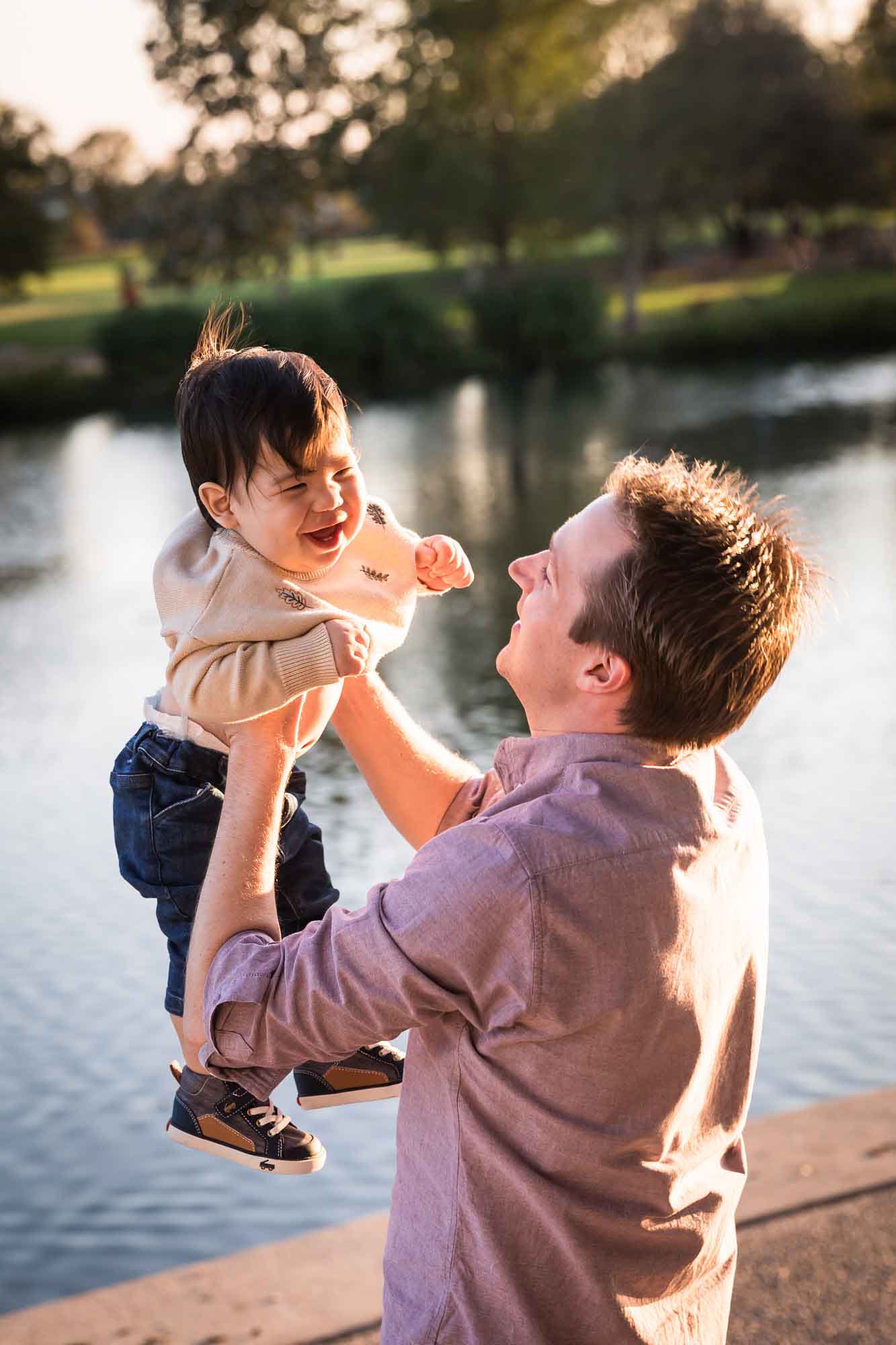 Little boy playing with father wearing pink shirt beside Mueller Lake during a Mueller Lake Park family portrait