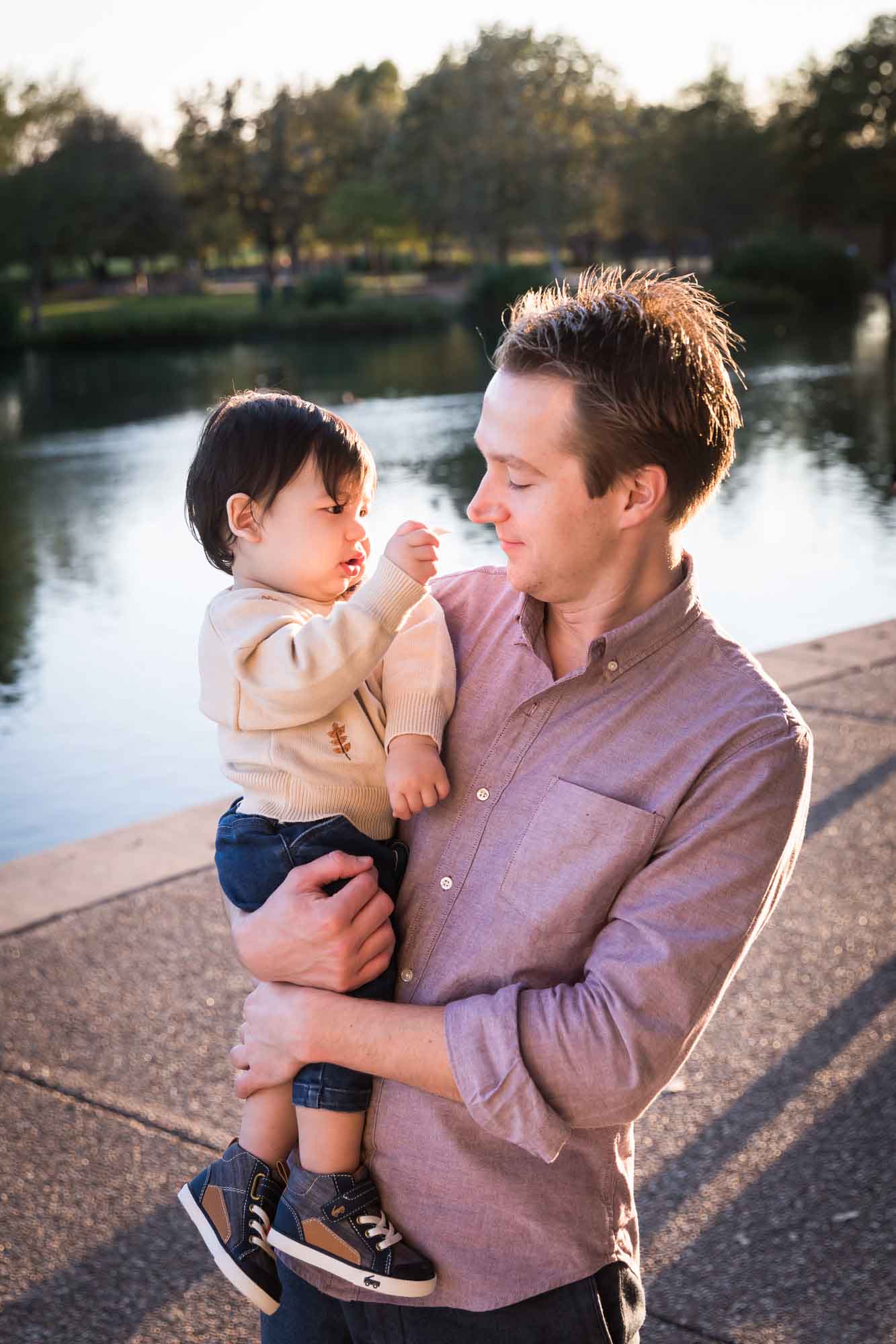 Little boy playing with father wearing pink shirt beside Mueller Lake during a Mueller Lake Park family portrait