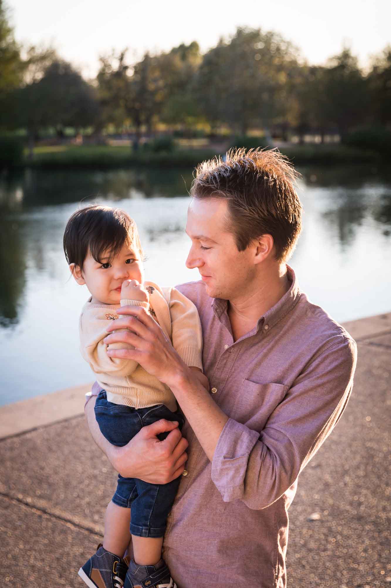 Little boy playing with father wearing pink shirt beside Mueller Lake during a Mueller Lake Park family portrait