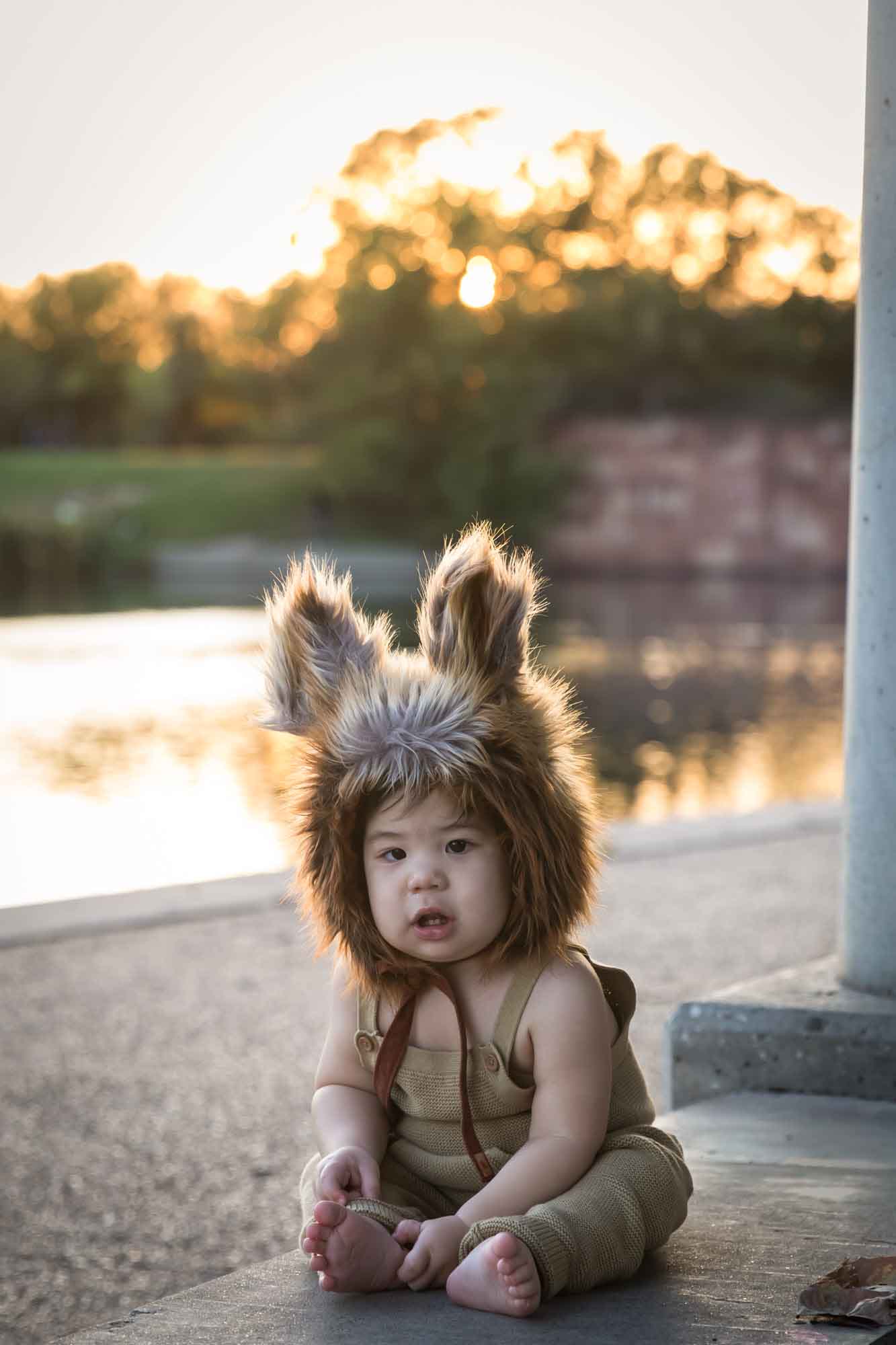 Little boy wearing furry fox hat beside Mueller Lake at sunset during a Mueller Lake Park family portrait