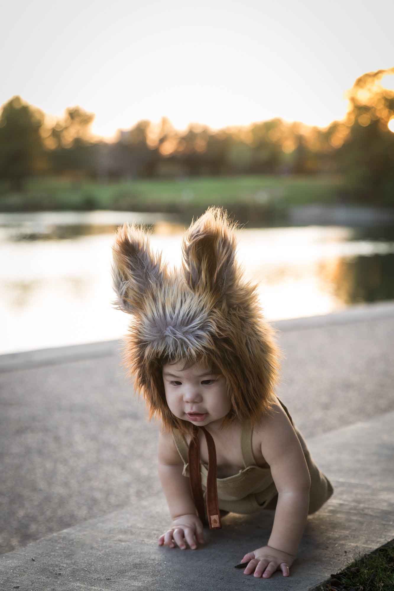 Little boy wearing furry fox hat beside Mueller Lake at sunset during a Mueller Lake Park family portrait