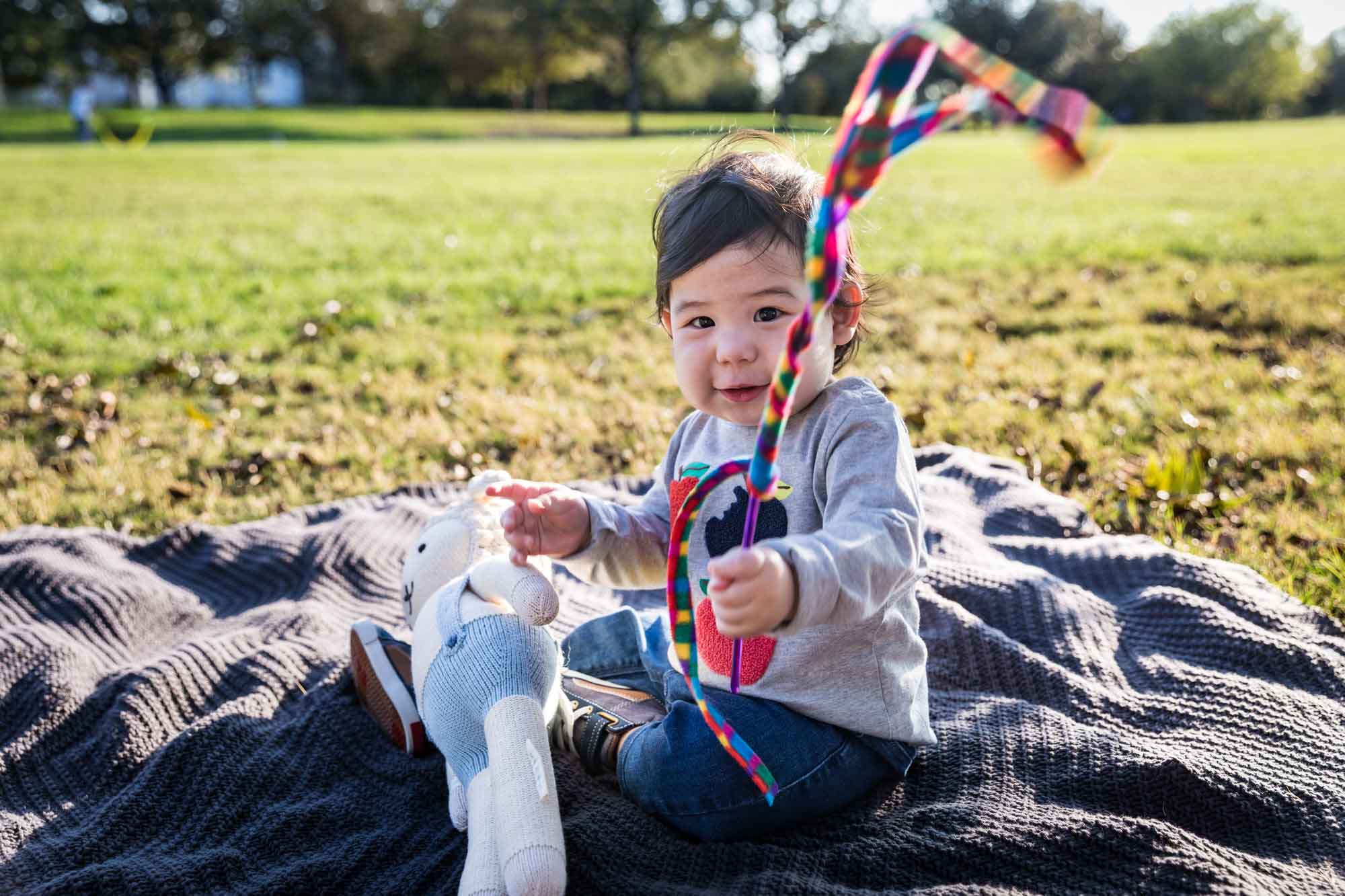 Little boy playing with toys while sitting on grass during a Mueller Lake Park family portrait