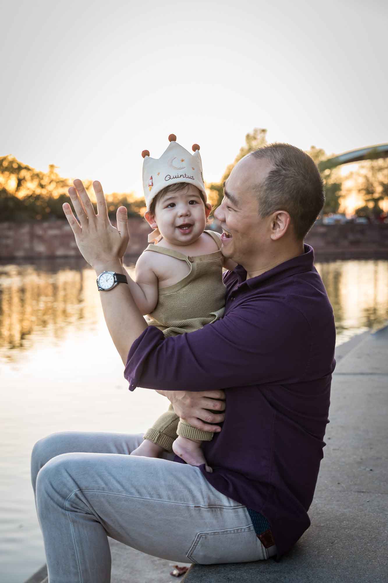 Father and little boy playing on concrete ground beside Mueller Lake during a Mueller Lake Park family portrait