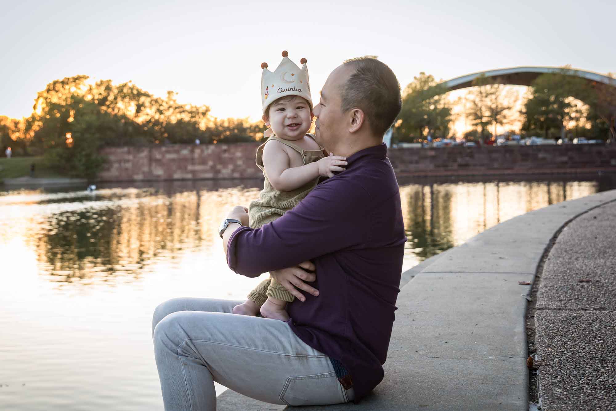Father and little boy playing on concrete ground beside Mueller Lake during a Mueller Lake Park family portrait