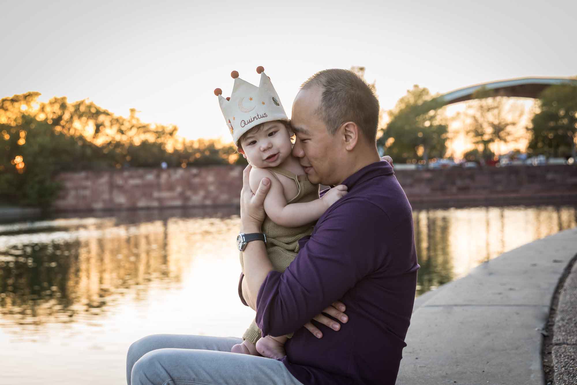Father and little boy playing on concrete ground beside Mueller Lake during a Mueller Lake Park family portrait