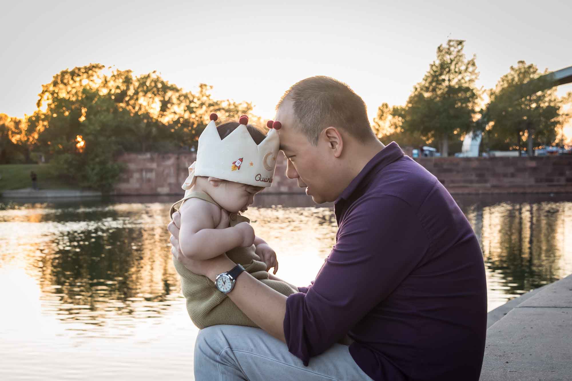 Father and little boy playing on concrete ground beside Mueller Lake during a Mueller Lake Park family portrait