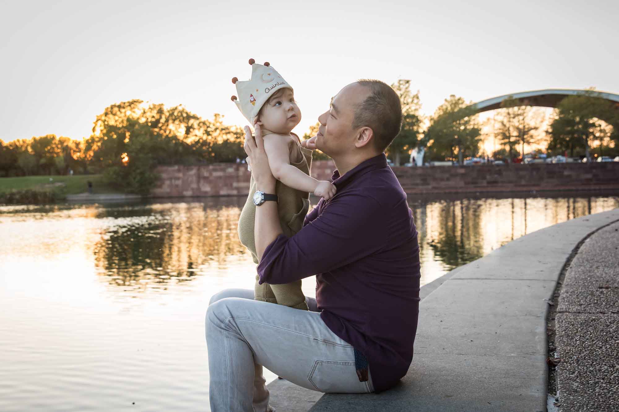 Father and little boy playing on concrete ground beside Mueller Lake during a Mueller Lake Park family portrait