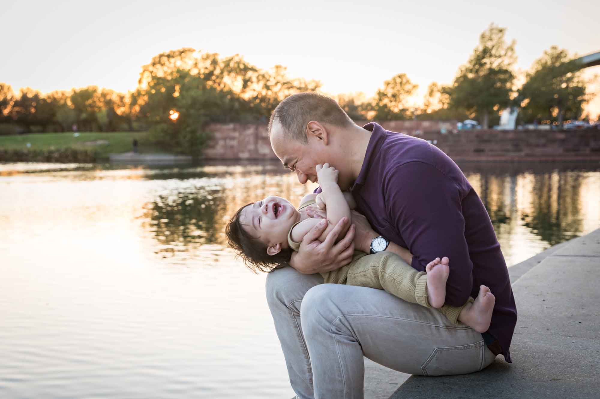 Father and little boy playing on concrete ground beside Mueller Lake during a Mueller Lake Park family portrait