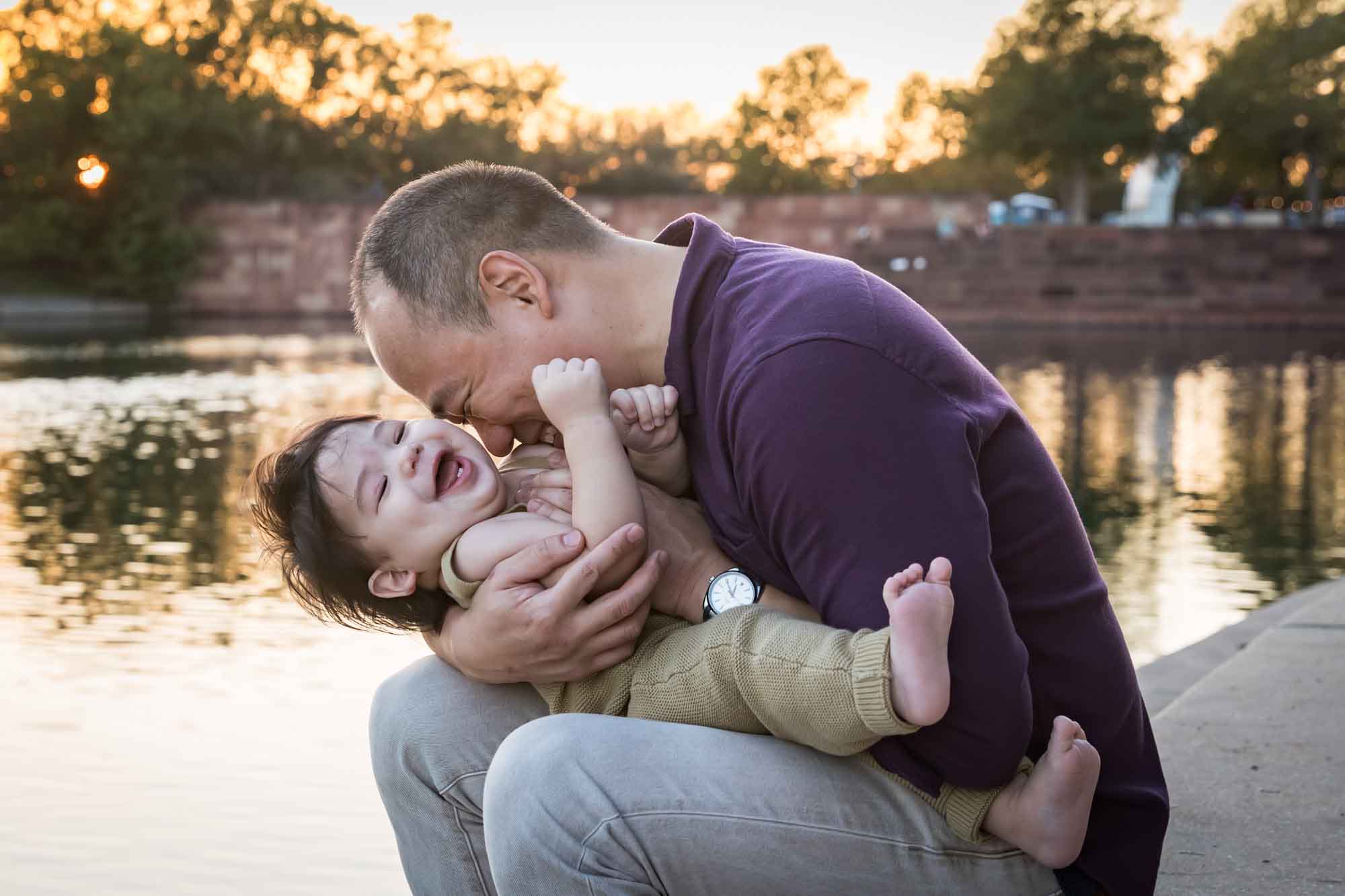 Father and little boy playing on concrete ground beside Mueller Lake during a Mueller Lake Park family portrait