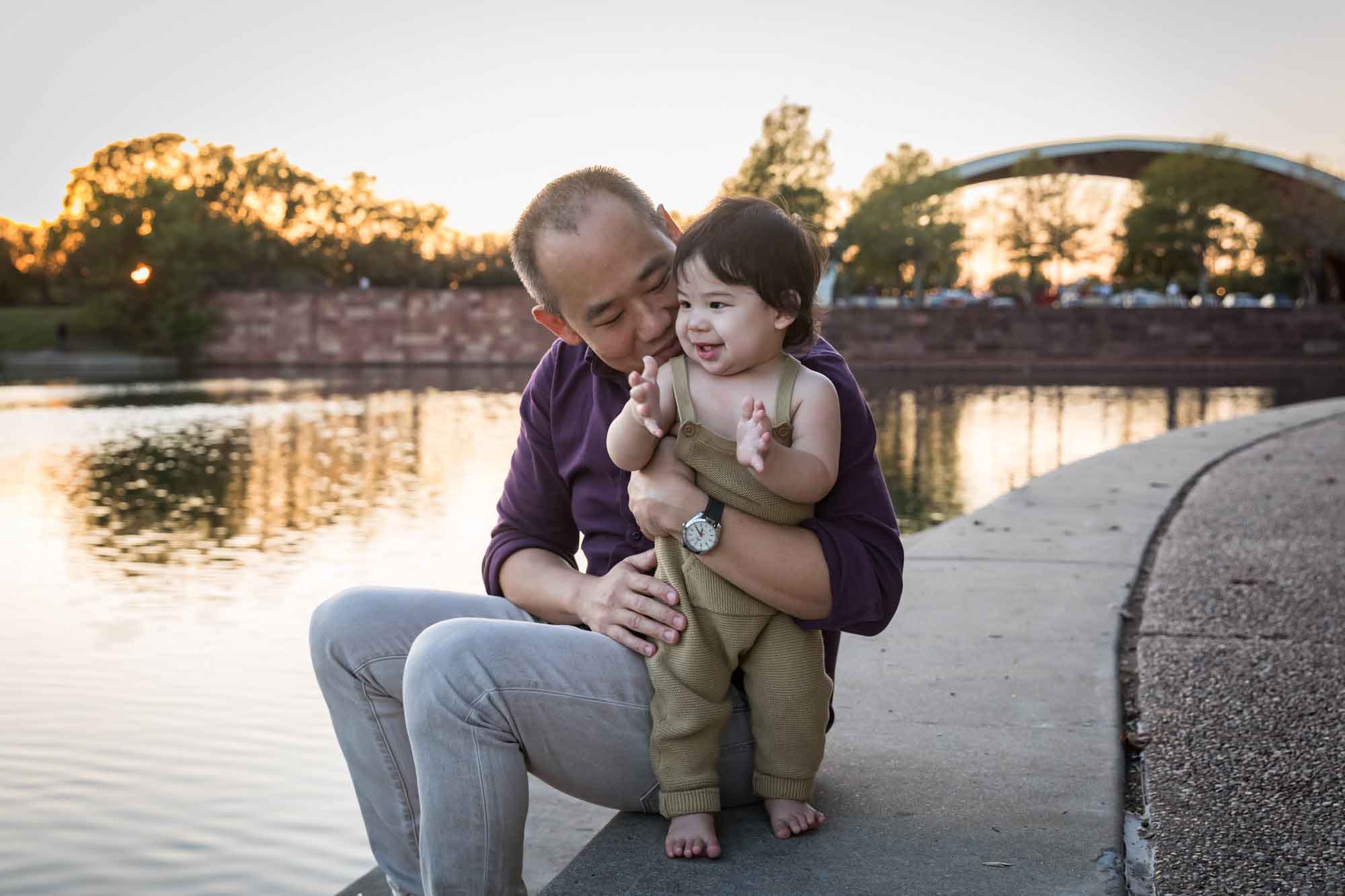 Father and little boy playing on concrete ground beside Mueller Lake during a Mueller Lake Park family portrait
