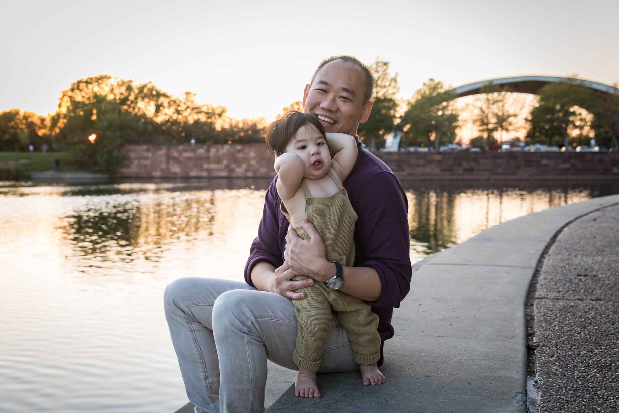 Father and little boy playing on concrete ground beside Mueller Lake during a Mueller Lake Park family portrait