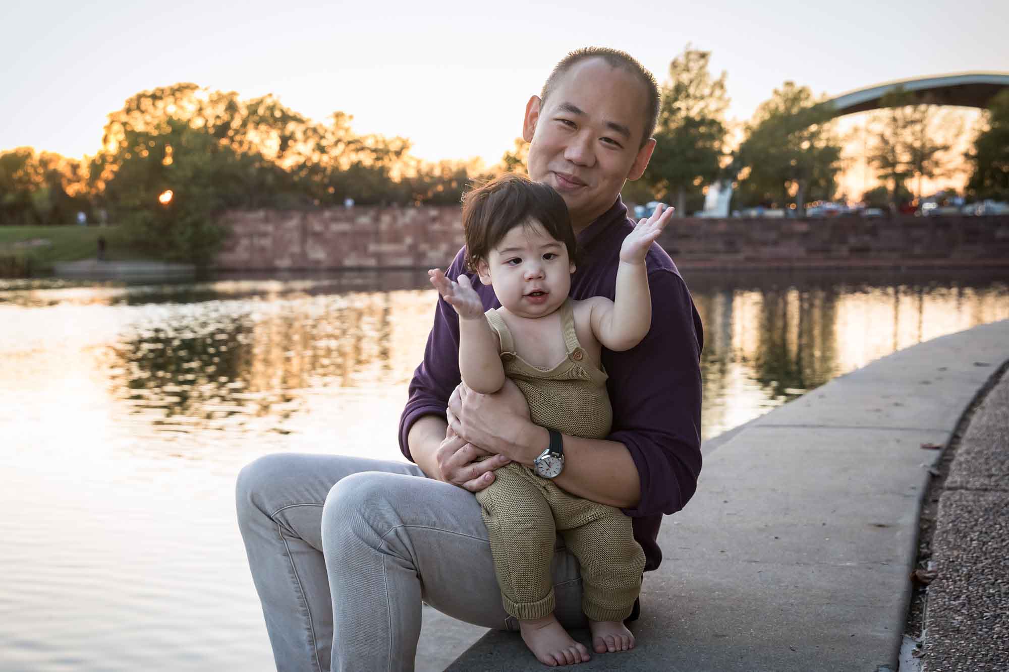 Father and little boy playing on concrete ground beside Mueller Lake during a Mueller Lake Park family portrait
