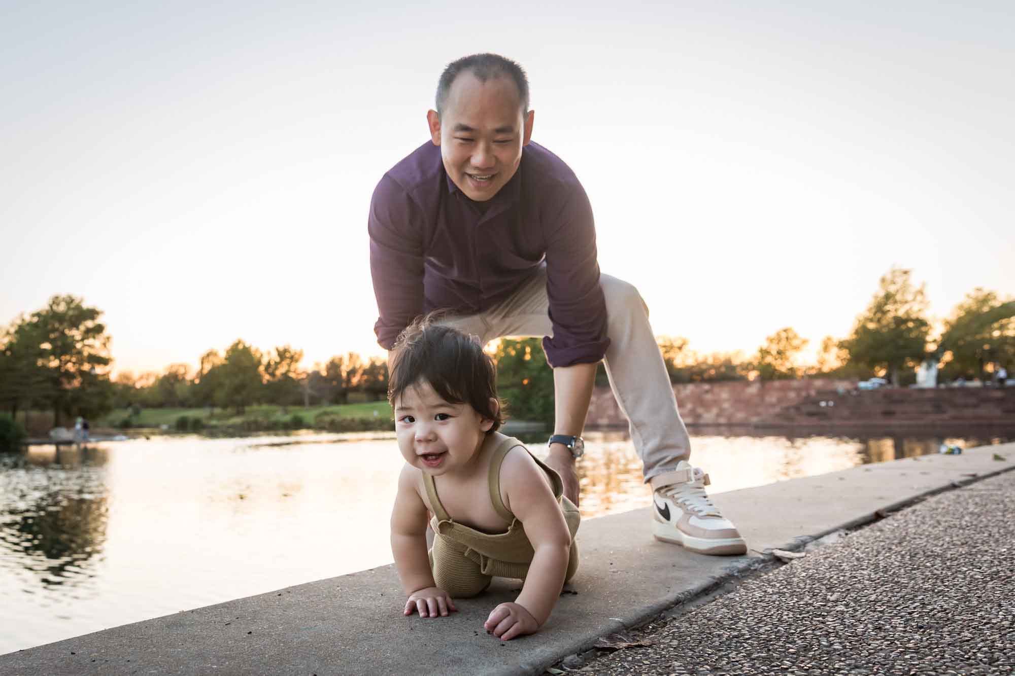 Father and little boy playing on concrete ground beside Mueller Lake during a Mueller Lake Park family portrait