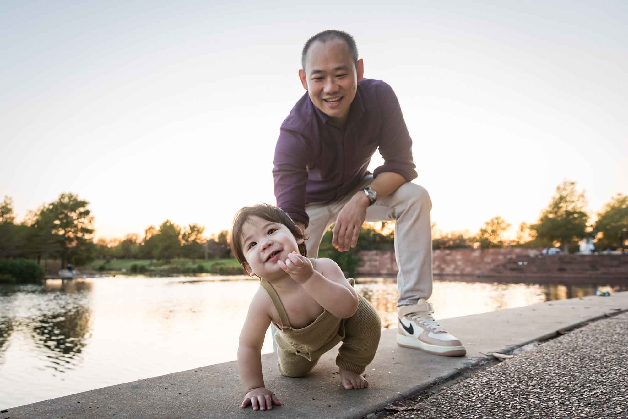 Father and little boy playing on concrete ground beside Mueller Lake during a Mueller Lake Park family portrait