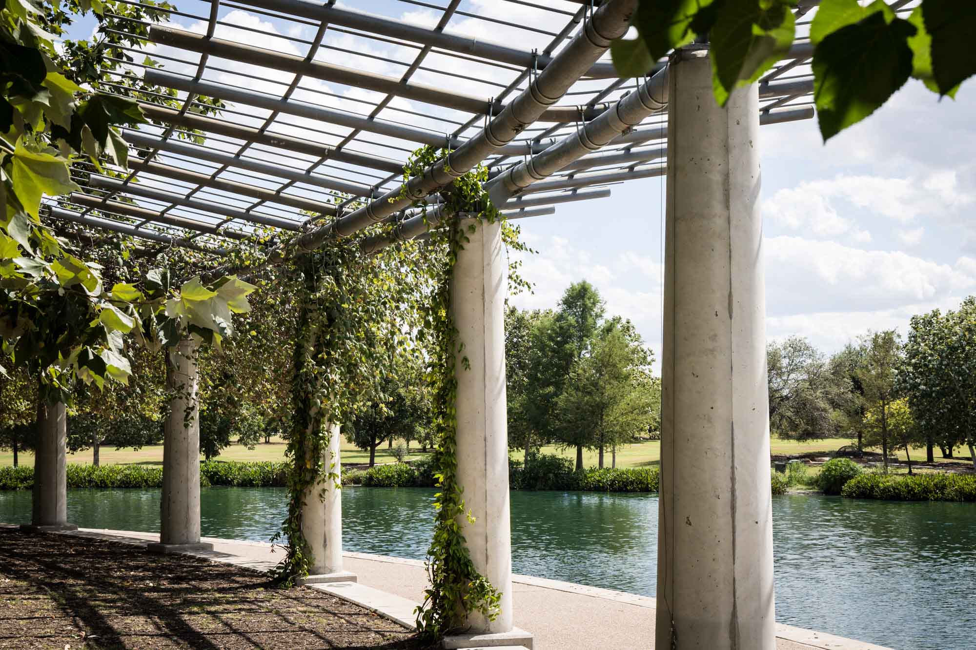 Colonnade wrapped in vines beside lake at Mueller Lake Park