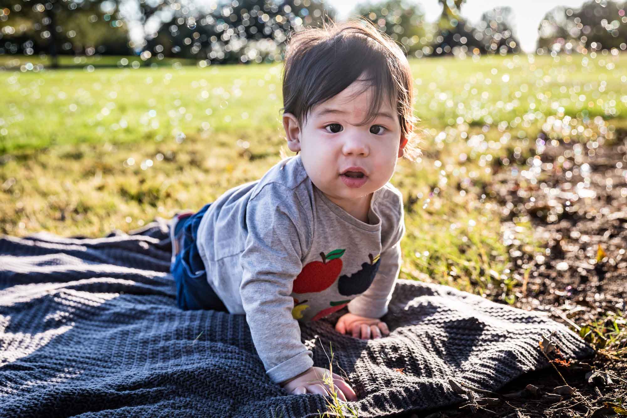 Little boy playing with bubbles while sitting on grass during a Mueller Lake Park family portrait