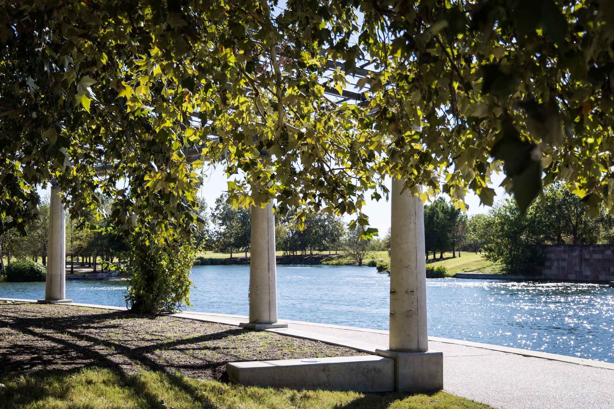Colonnade with trees beside lake at Mueller Lake Park