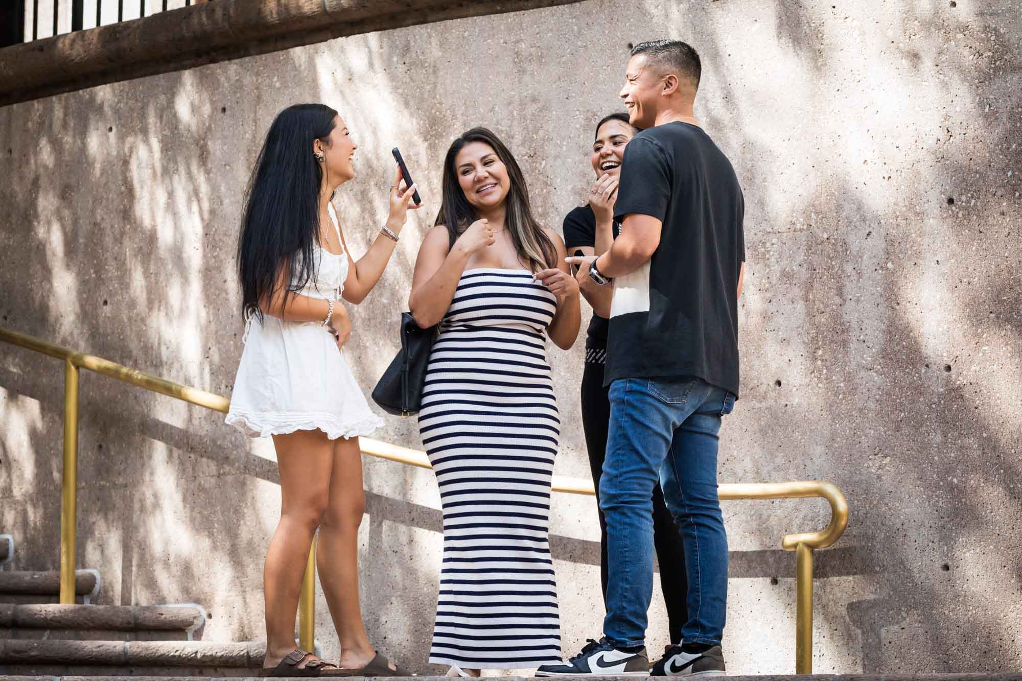 Woman, man, and two daughters looking at phone after Riverwalk surprise proposal in San Antonio