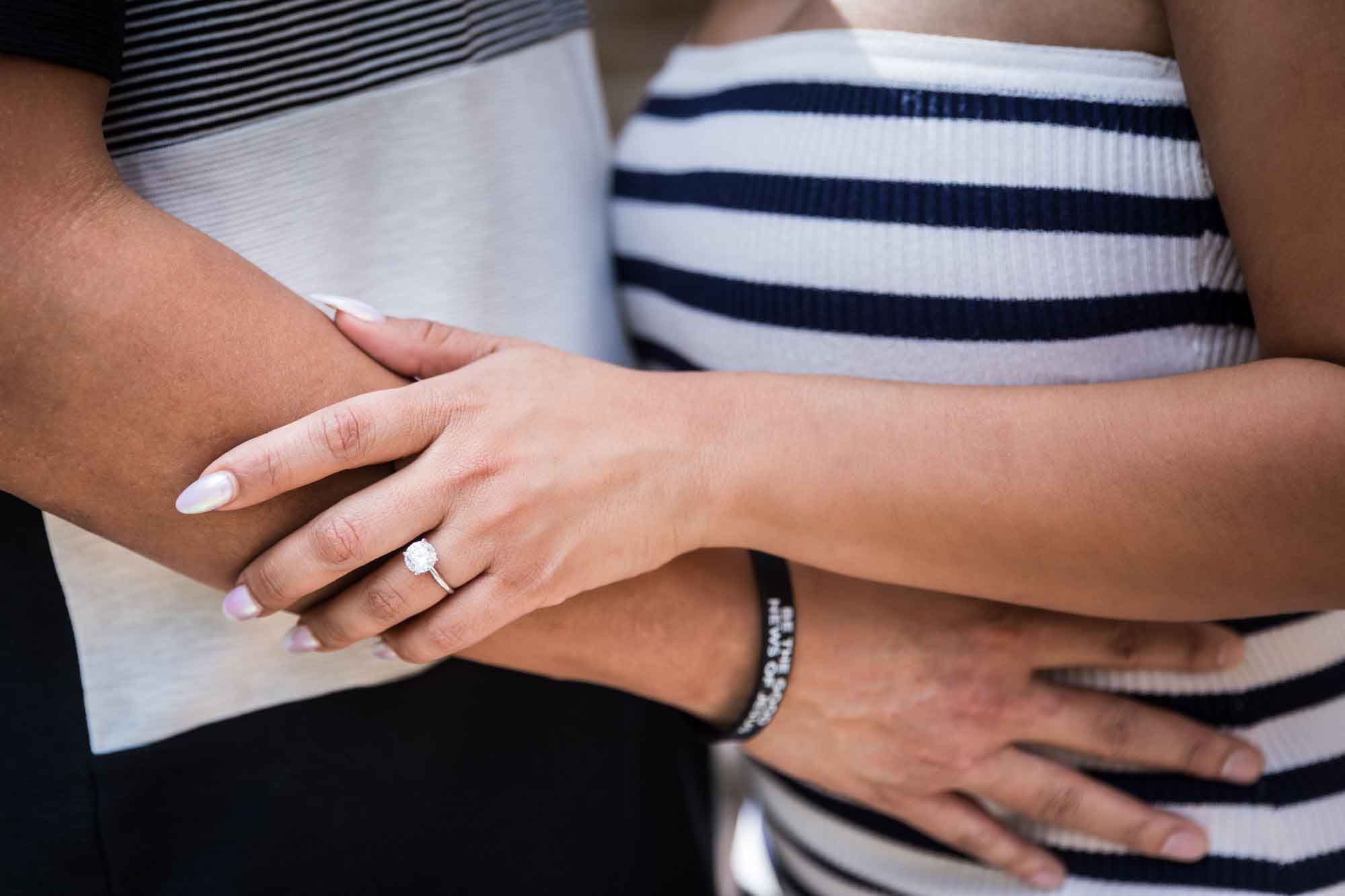 Close up of woman's arm showing her hand with engagement ring resting on man's arm