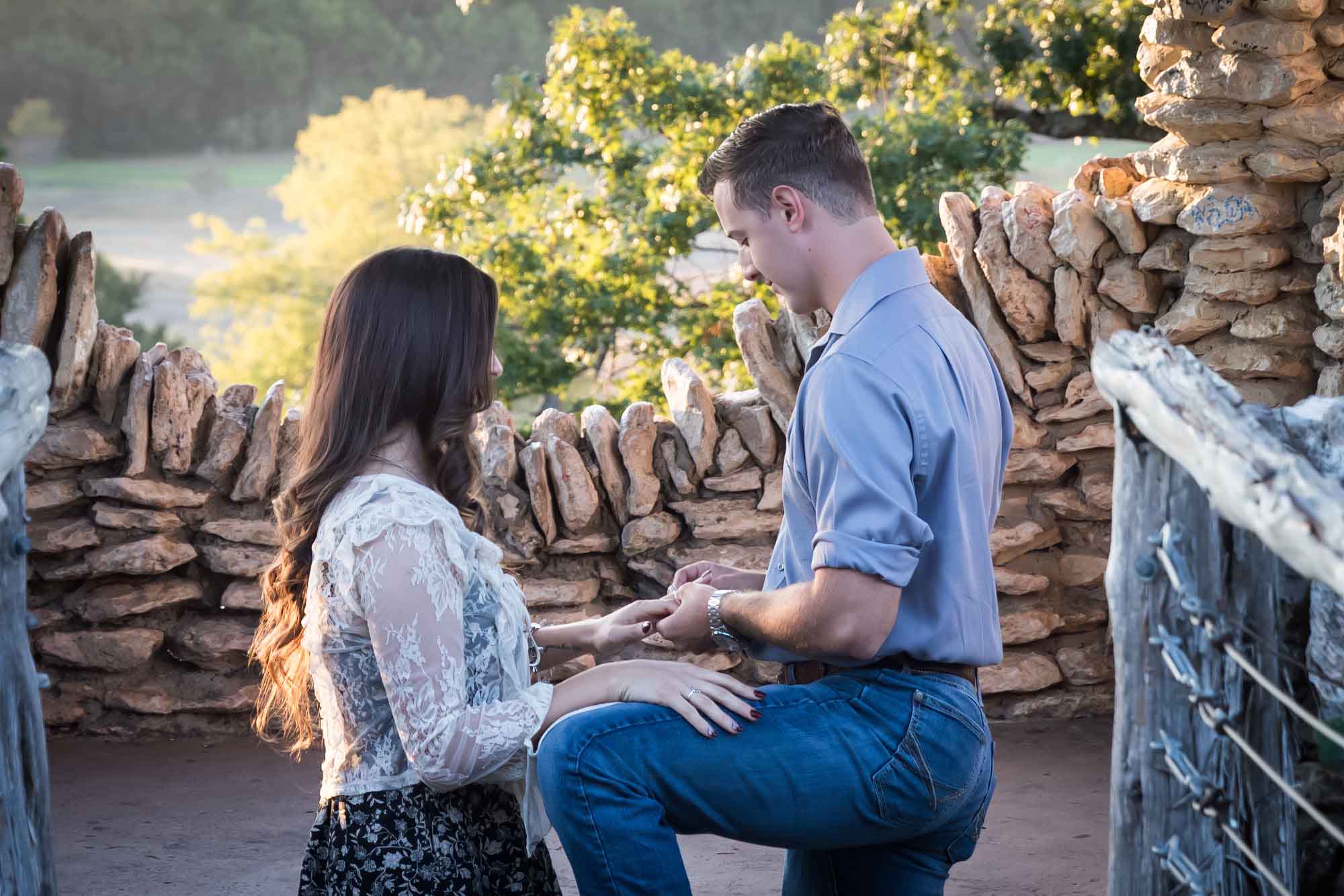 Man proposing on one knee to woman in middle of stone building during Japanese Tea Garden surprise proposal by Kelly Williams San Antonio wedding photographer